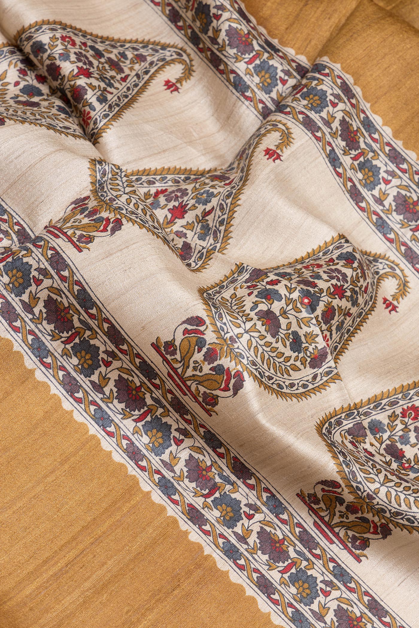 Close up of Mustard Tussar Silk Saree with Zari Butta on the body and Zari Border.  displaying folds