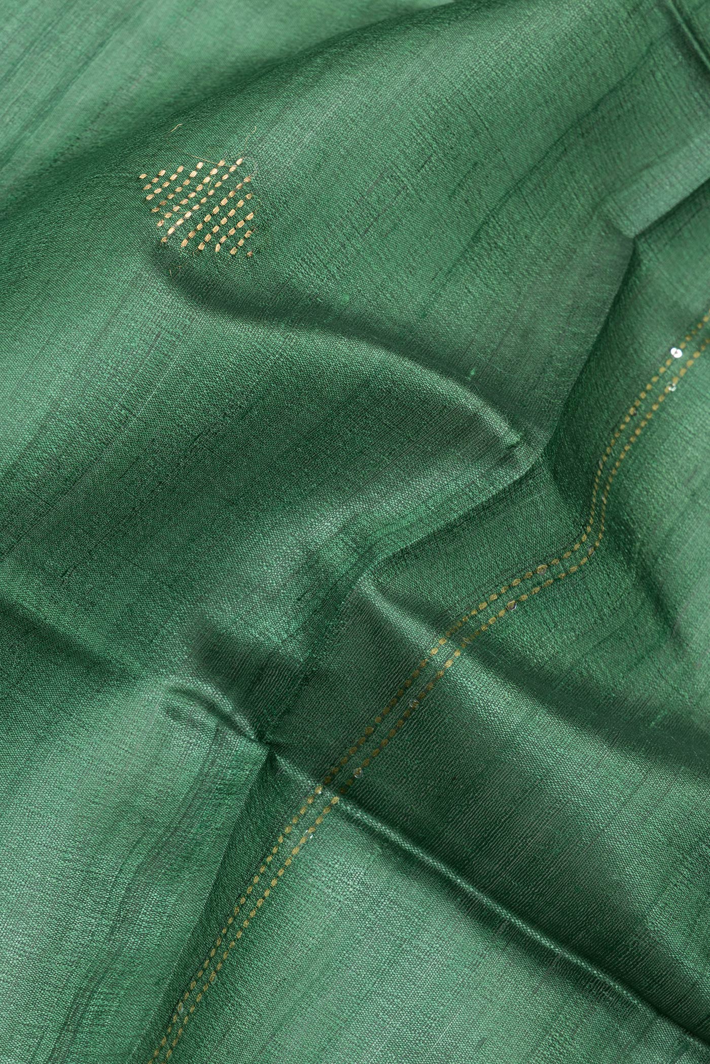 Close up of Green Tussar Silk Saree with Embroidery on the body and Zari Border.  displaying folds
