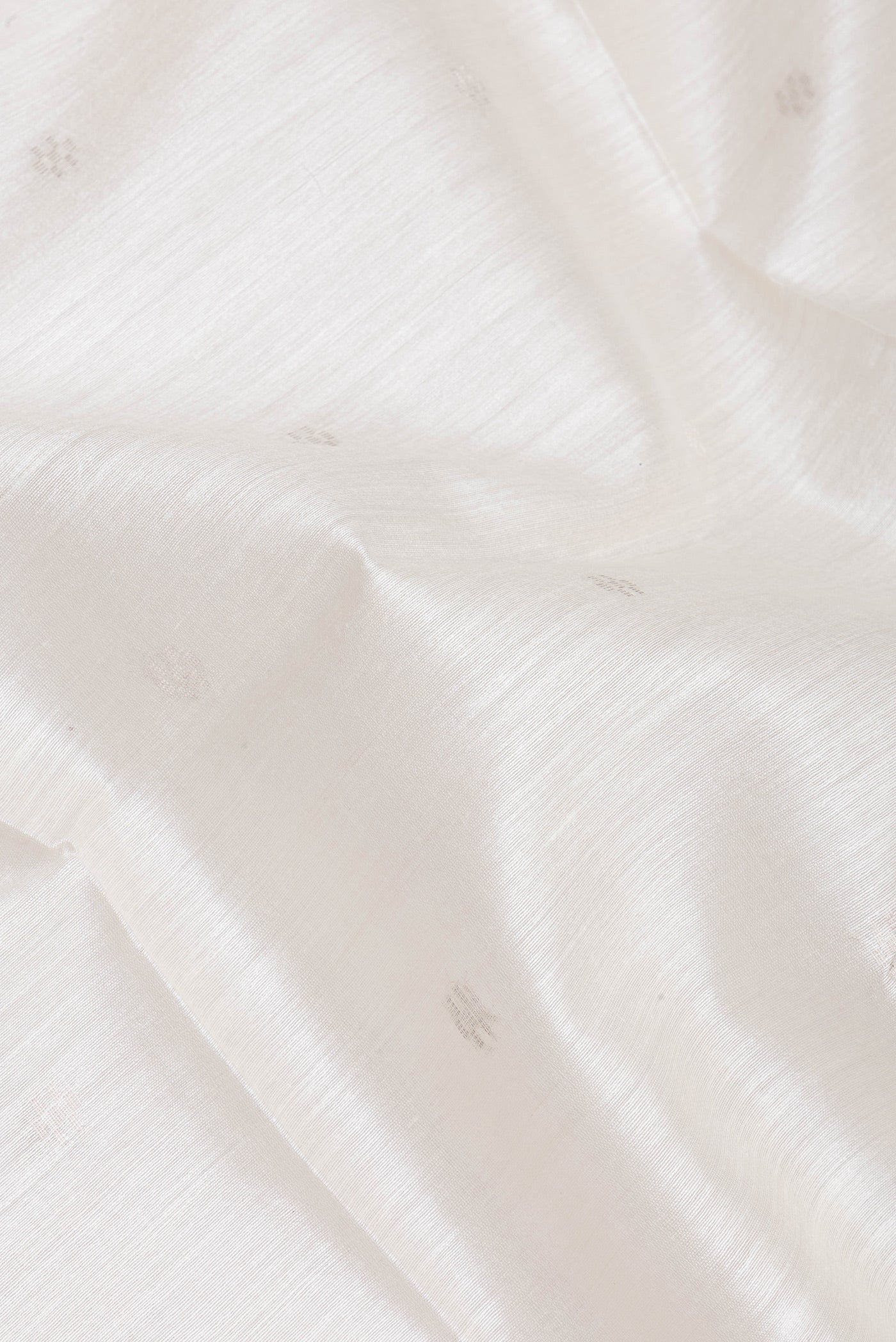 Close up of White Tussar Silk Saree with Zari Butta on the body and Zari Border.  displaying folds