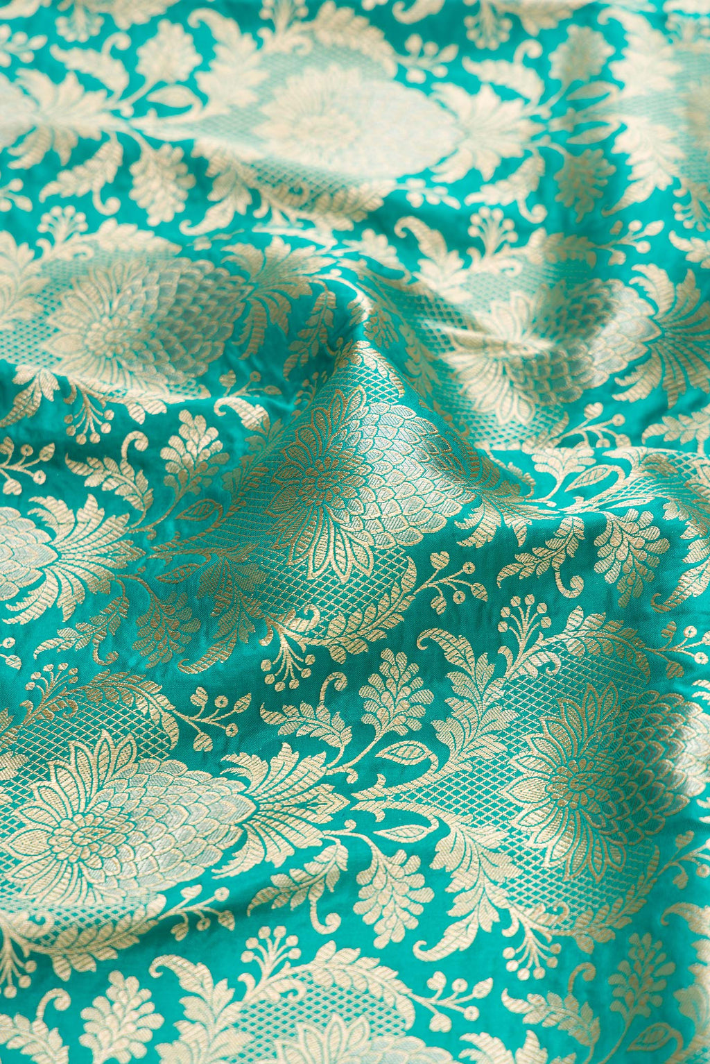 Close up of Turquoise Banarasi Silk Saree with Zari Brocade on the body and Zari Border.  displaying folds