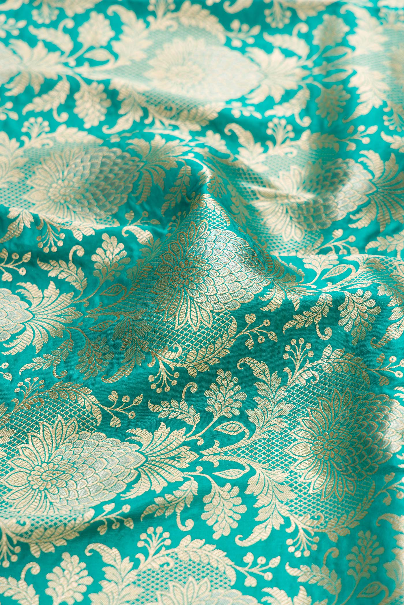 Close up of Turquoise Banarasi Silk Saree with Zari Brocade on the body and Zari Border.  displaying folds