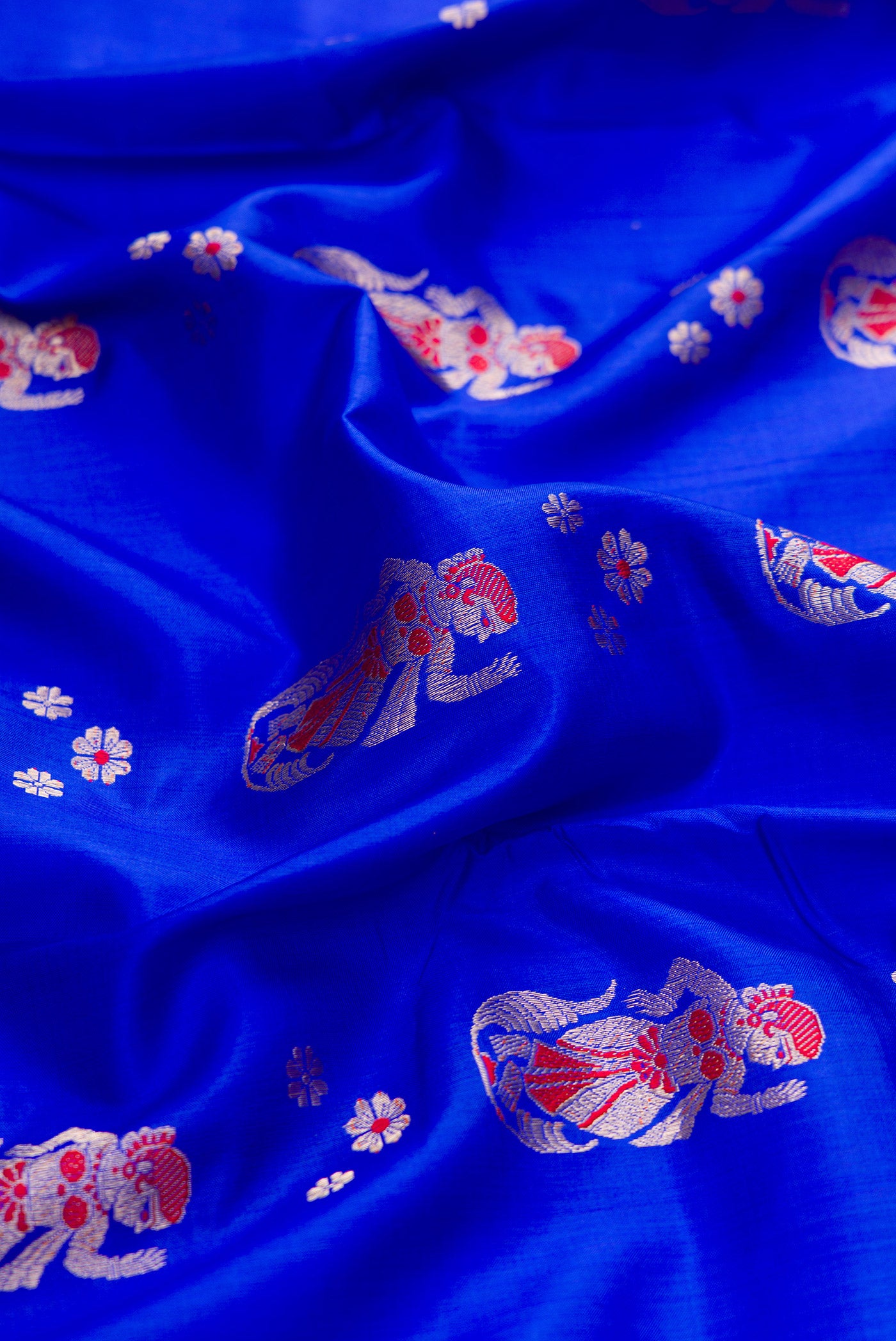 Close up of Royal Blue Baluchari Silk Saree with Zari And Thread Butta on the body and Zari And Thread Border.  displaying folds