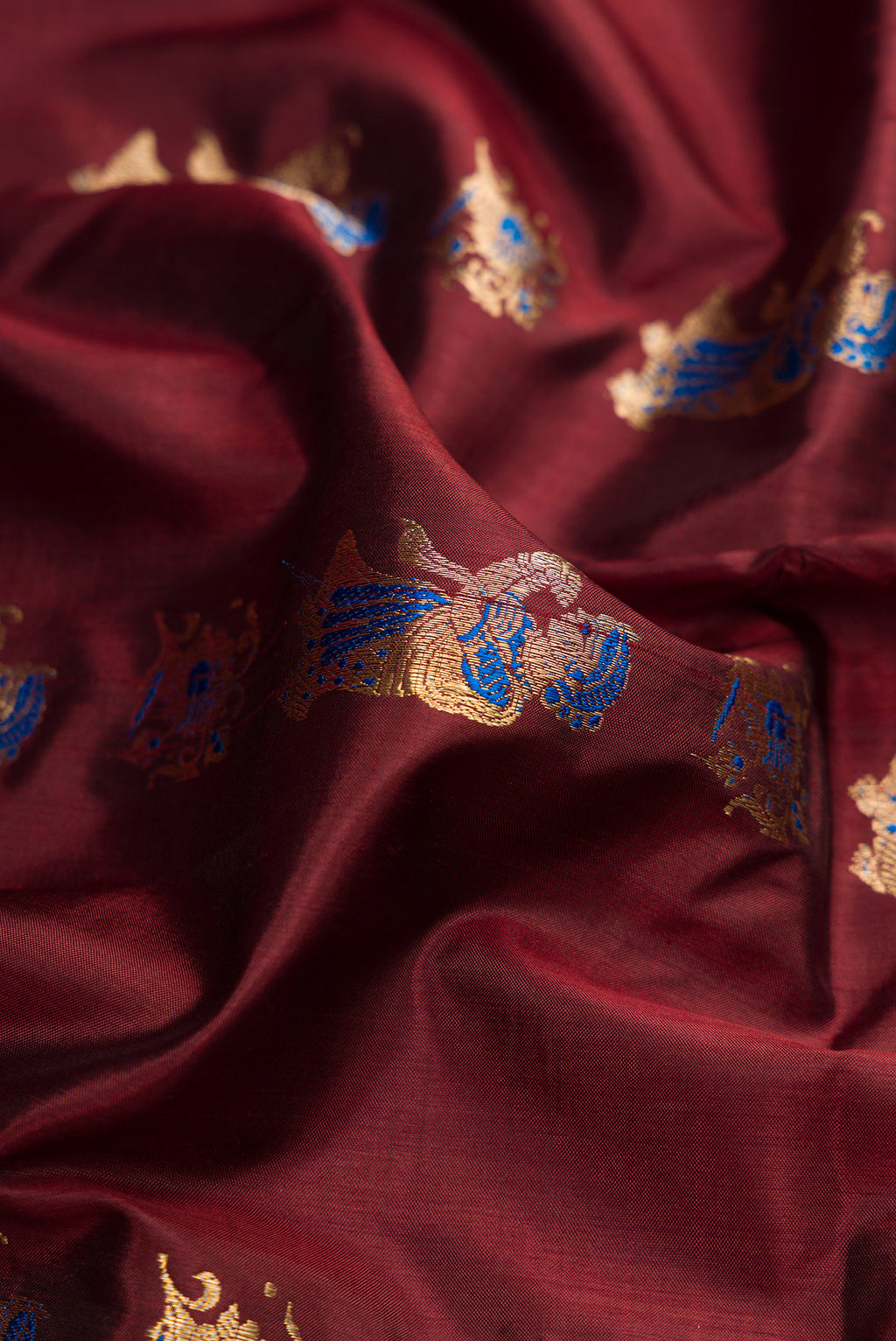 Close up of Coffee Brown Baluchari Silk Saree with Zari And Thread Butta on the body and Zari Border.  displaying folds