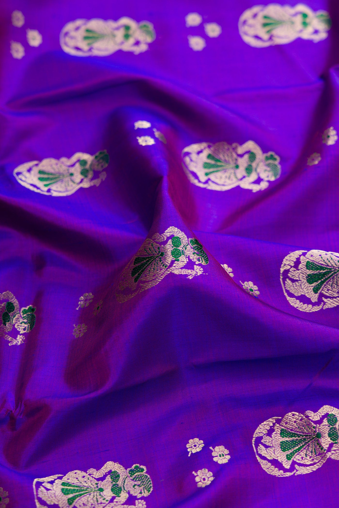 Close up of Purple Dual Tone Baluchari Silk Saree with Zari And Thread Butta on the body and Zari Border.  displaying folds