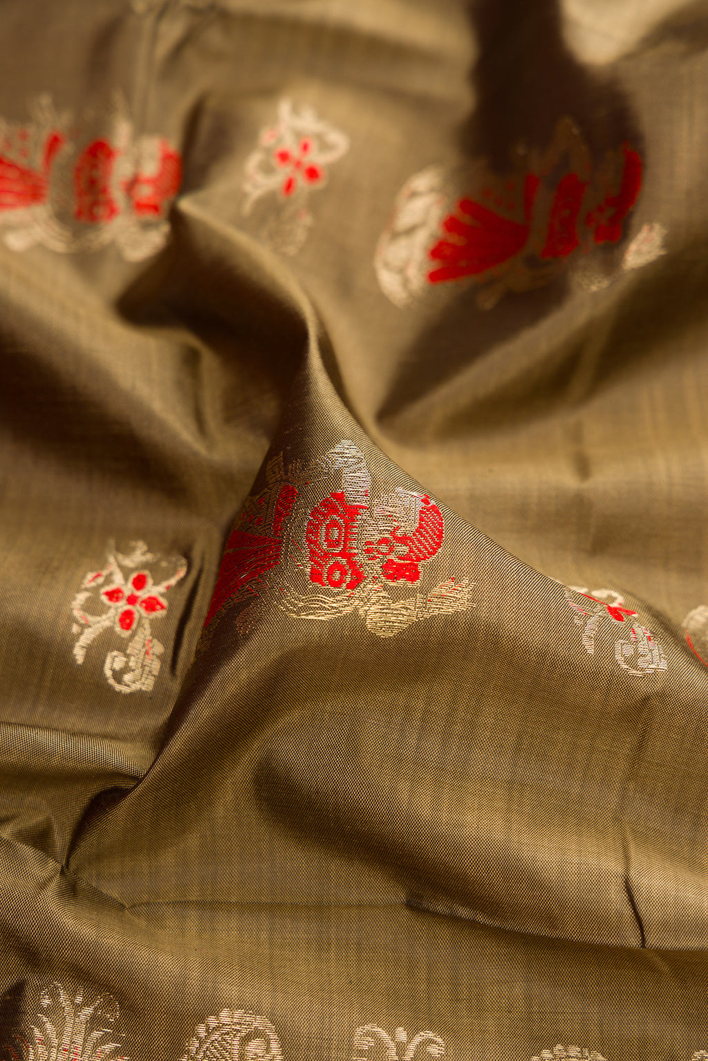 Close up of Dark Beige Baluchari Silk Saree with Zari And Thread Butta on the body and Zari Border.  displaying folds