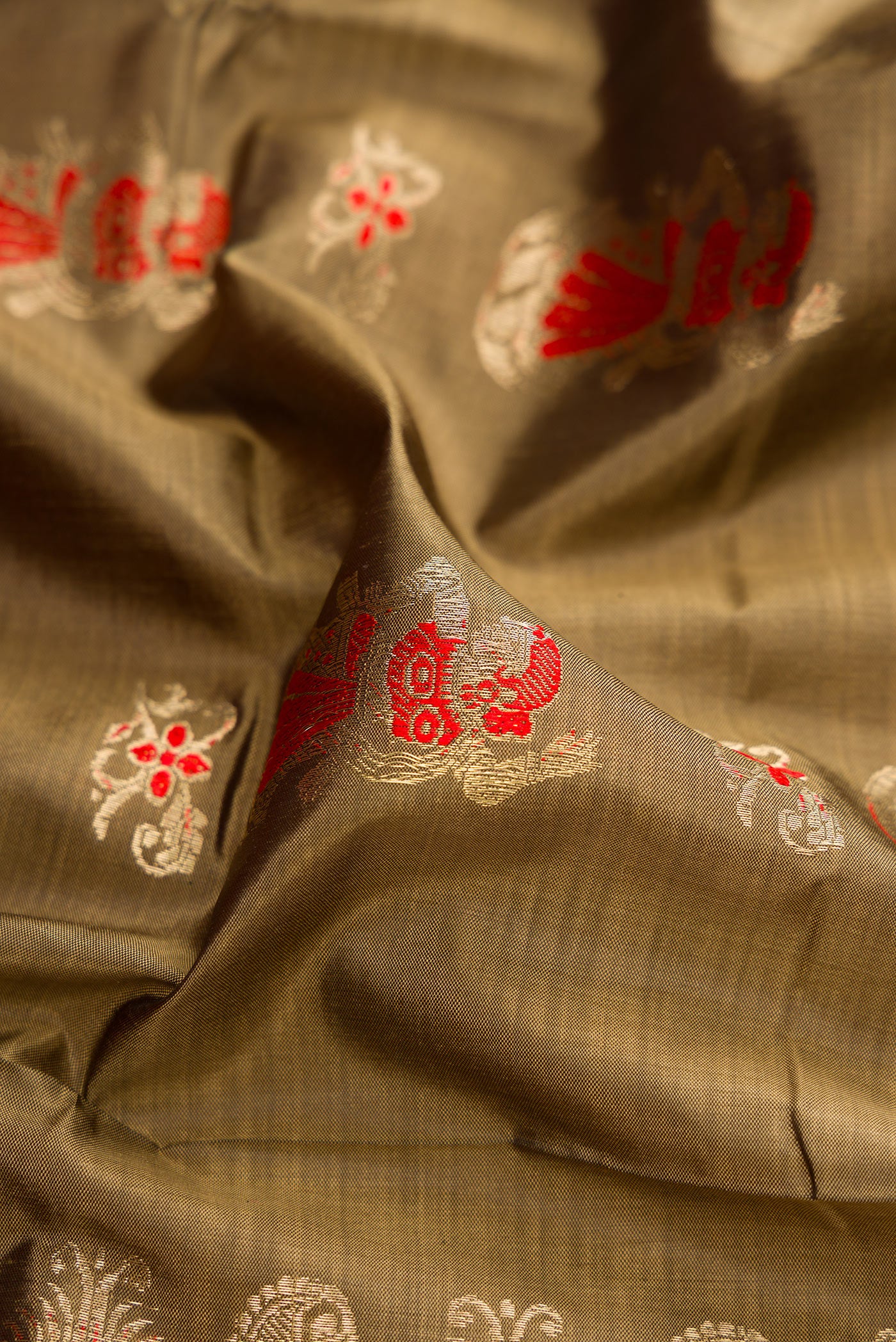 Close up of Dark Beige Baluchari Silk Saree with Zari And Thread Butta on the body and Zari Border.  displaying folds