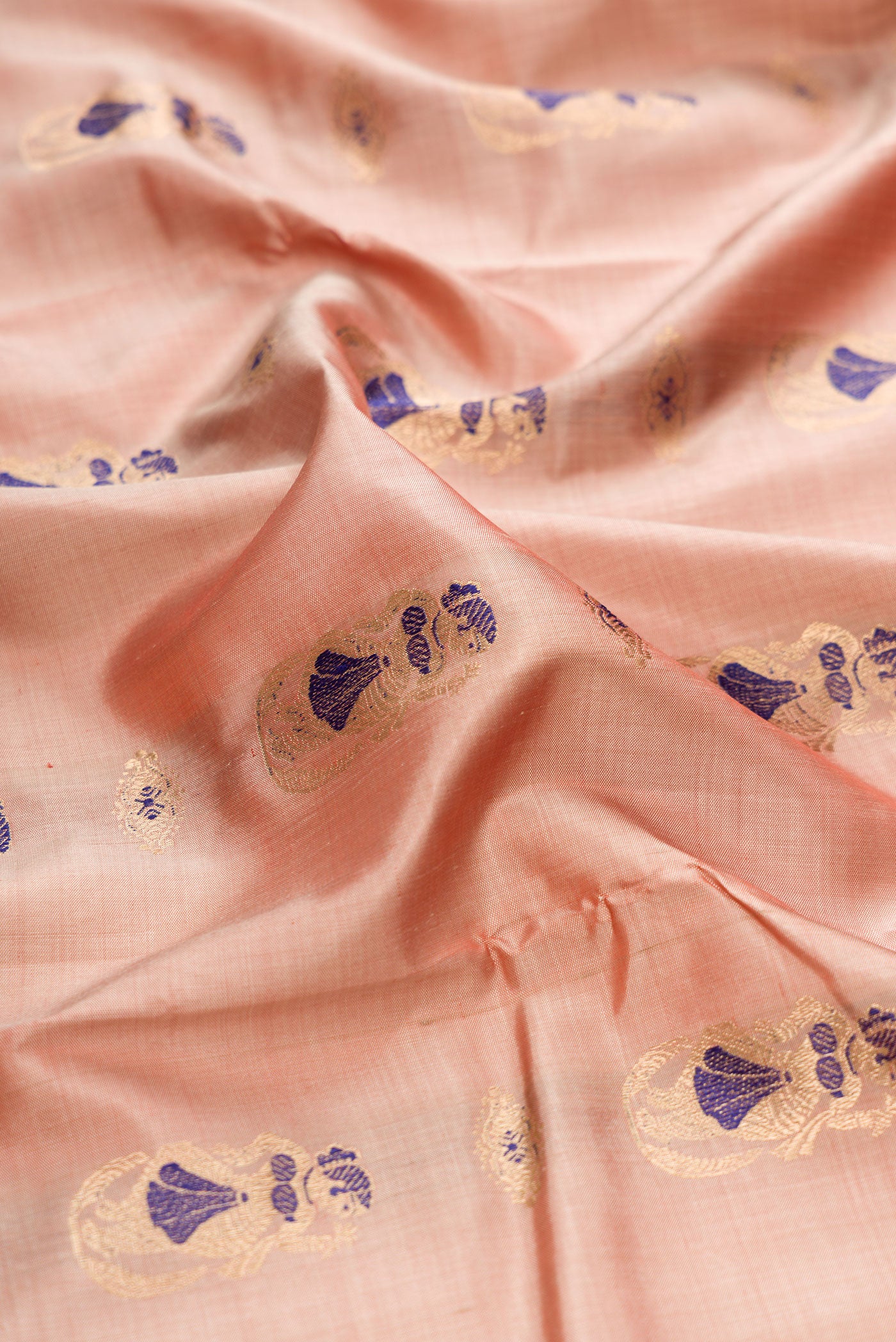Close up of Rose Gold Baluchari Silk Saree with Zari And Thread Butta on the body and Zari And Thread Border.  displaying folds