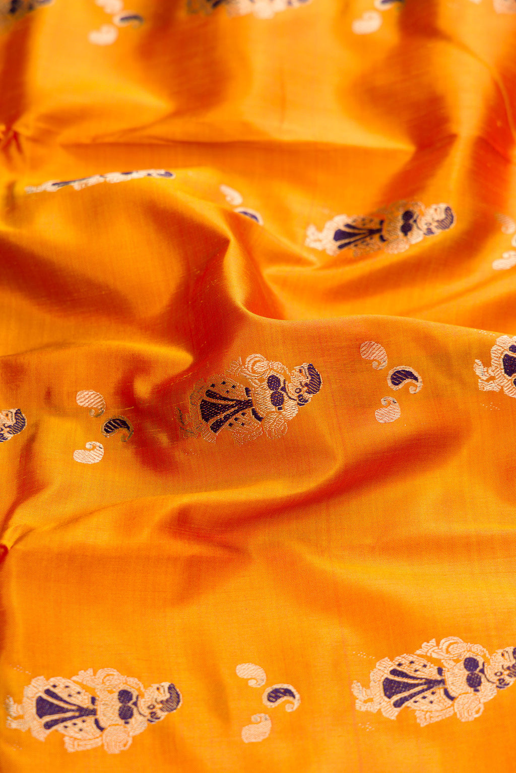 Close up of Mustard Baluchari Silk Saree with Zari And Thread Butta on the body and Zari Border.  displaying folds