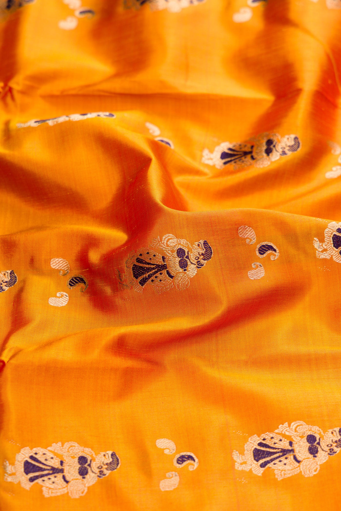 Close up of Mustard Baluchari Silk Saree with Zari And Thread Butta on the body and Zari Border.  displaying folds