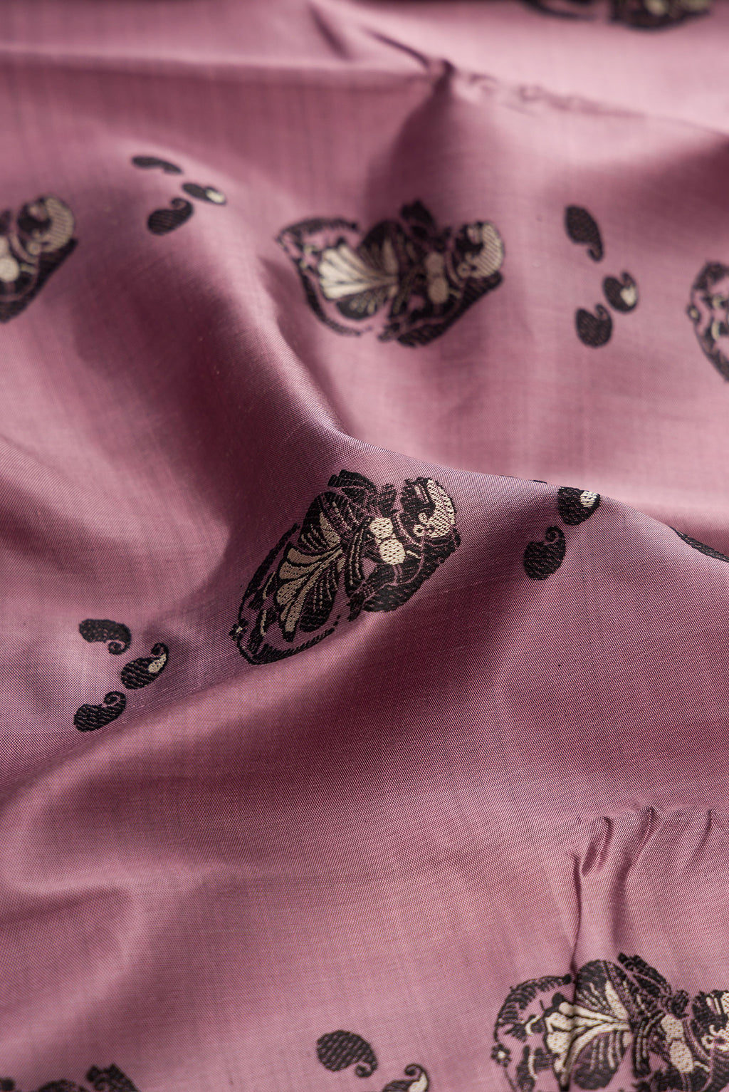 Close up of Mauve Baluchari Silk Saree with Thread Butta on the body and Thread Border.  displaying folds
