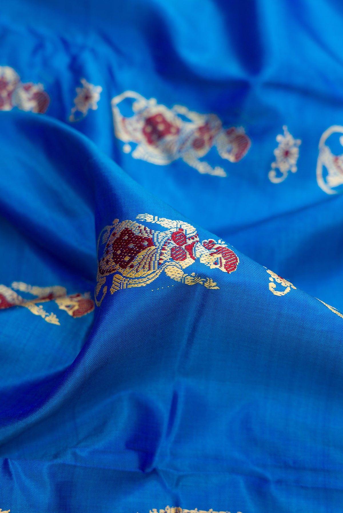 Close up of Royal Blue Baluchari Silk Saree with Thread Butta on the body and Thread Border.  displaying folds