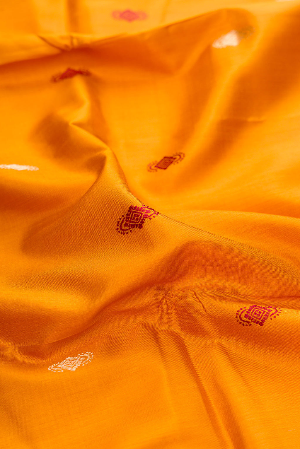 Close up of Mustard Baluchari Silk Saree with Zari And Thread Butta on the body and Zari And Thread Border.  displaying folds
