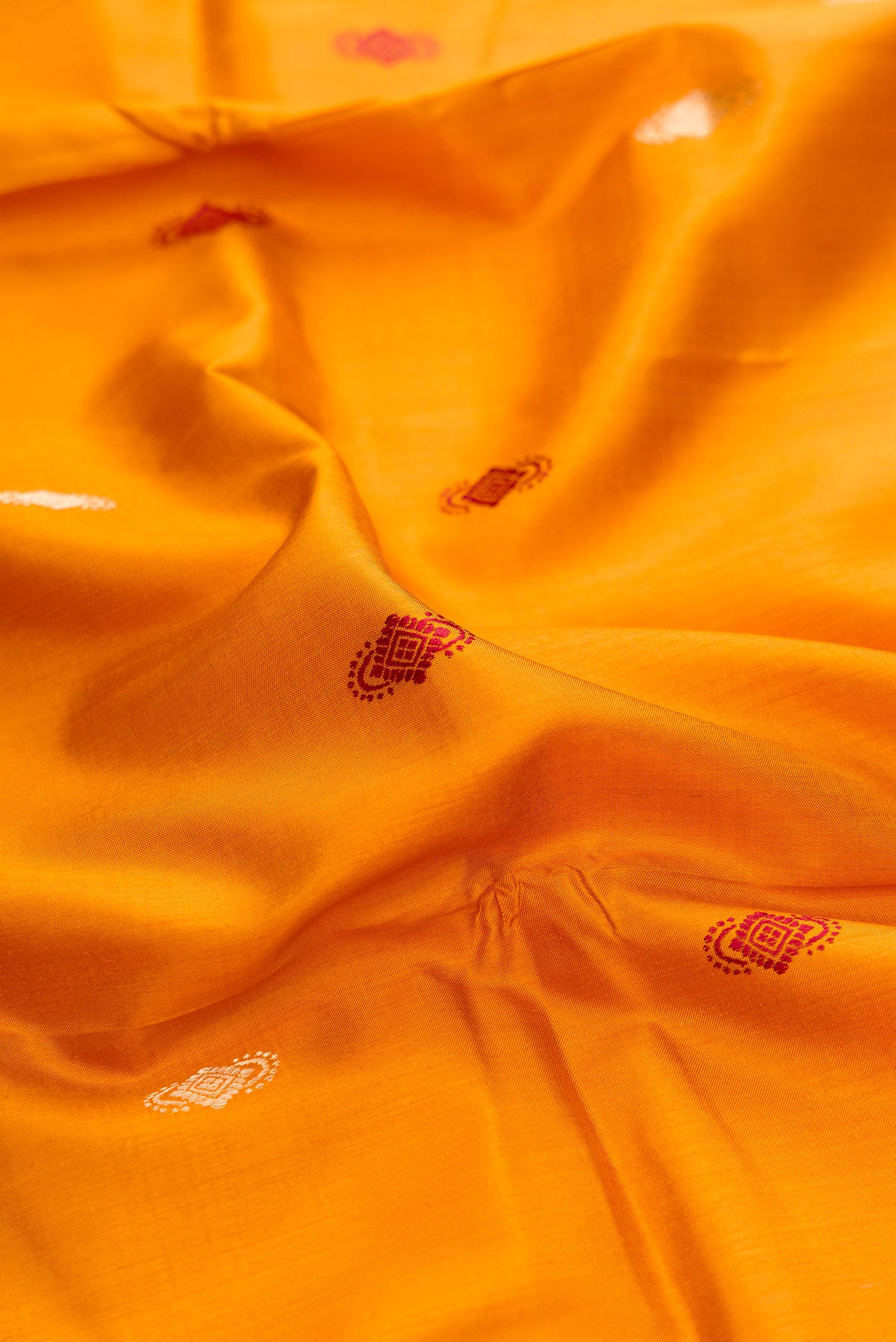 Close up of Mustard Baluchari Silk Saree with Zari And Thread Butta on the body and Zari And Thread Border.  displaying folds