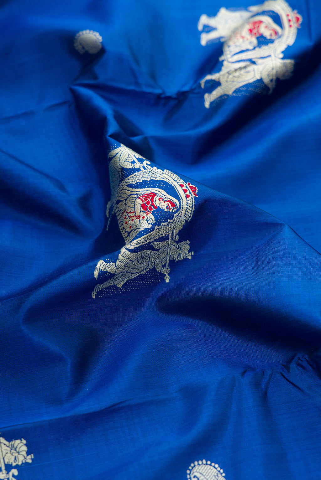 Close up of Royal Blue Baluchari Silk Saree with Thread Butta on the body and Thread Border.  displaying folds