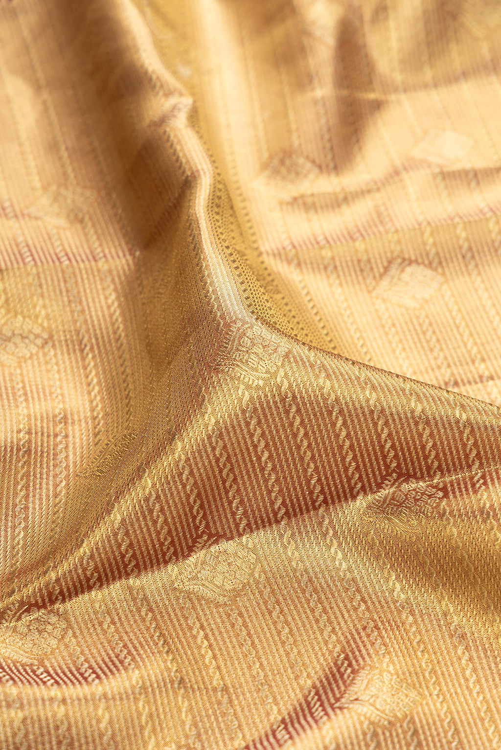 Close up of Gold Dual Tone Kanchipuram Tissue Silk Saree with Zari Brocade on the body and Zari Border.  displaying folds