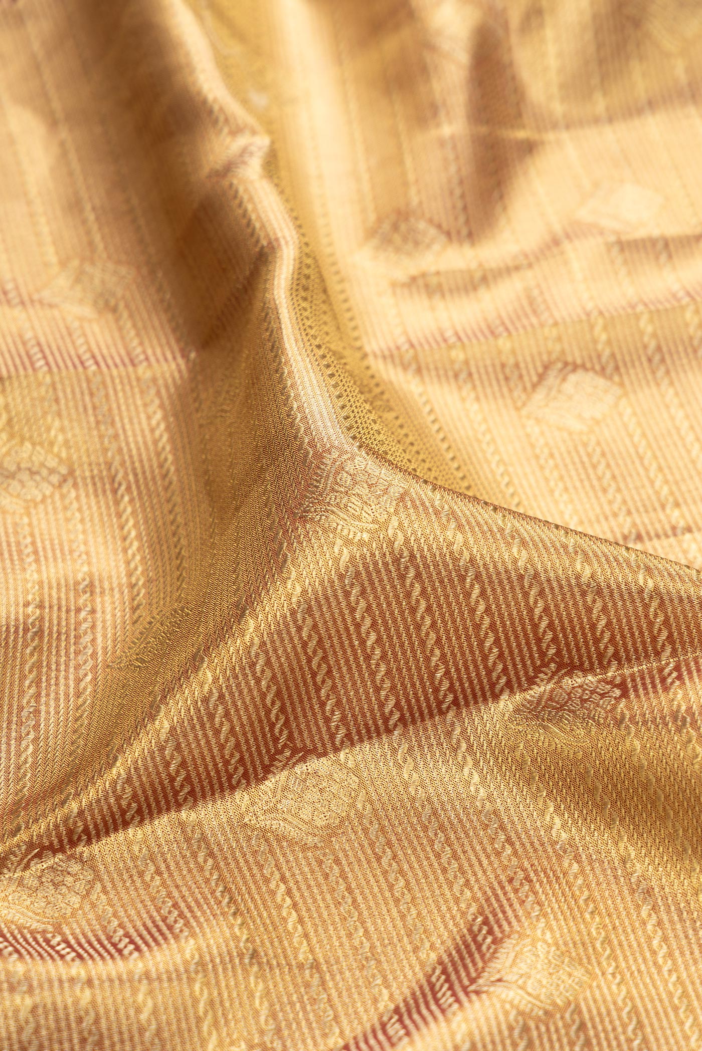 Close up of Gold Dual Tone Kanchipuram Tissue Silk Saree with Zari Brocade on the body and Zari Border.  displaying folds