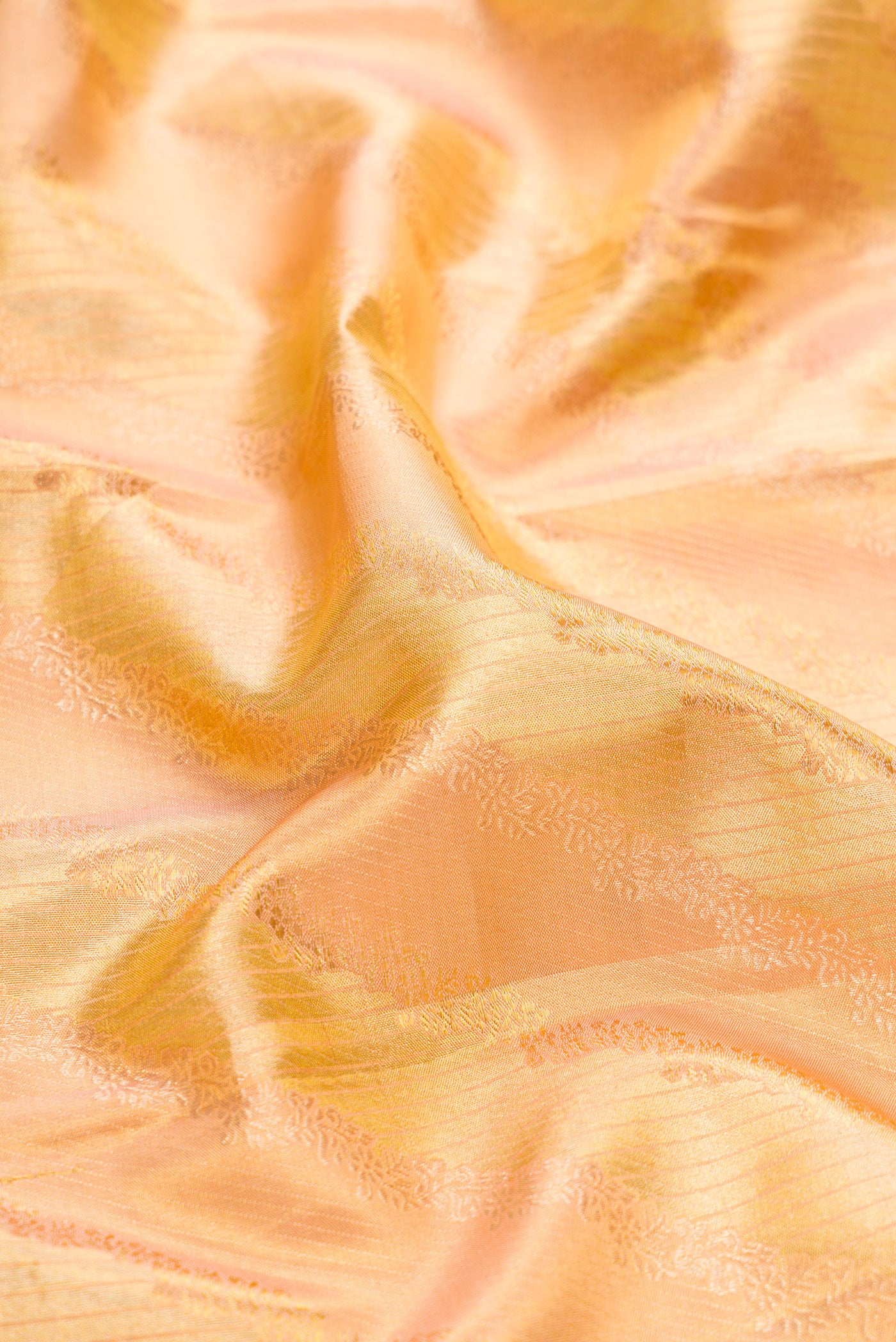 Close up of Golden Peach Dual Tone Kanchipuram Tissue Silk Saree with Zari Brocade on the body and Zari Border.  displaying folds