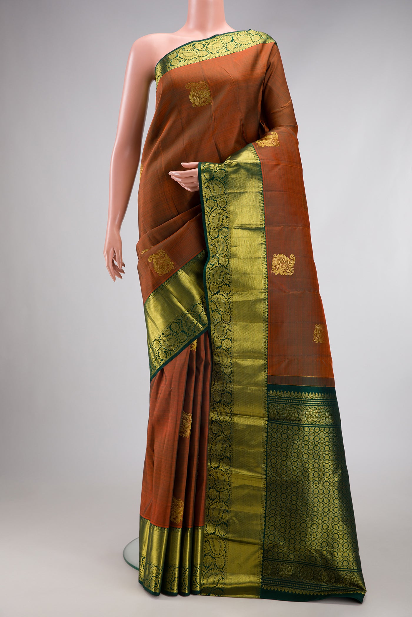 Rust Kanjivaram Silk Saree with Zari Butta on the body and Zari Border.  displayed on a mannequin