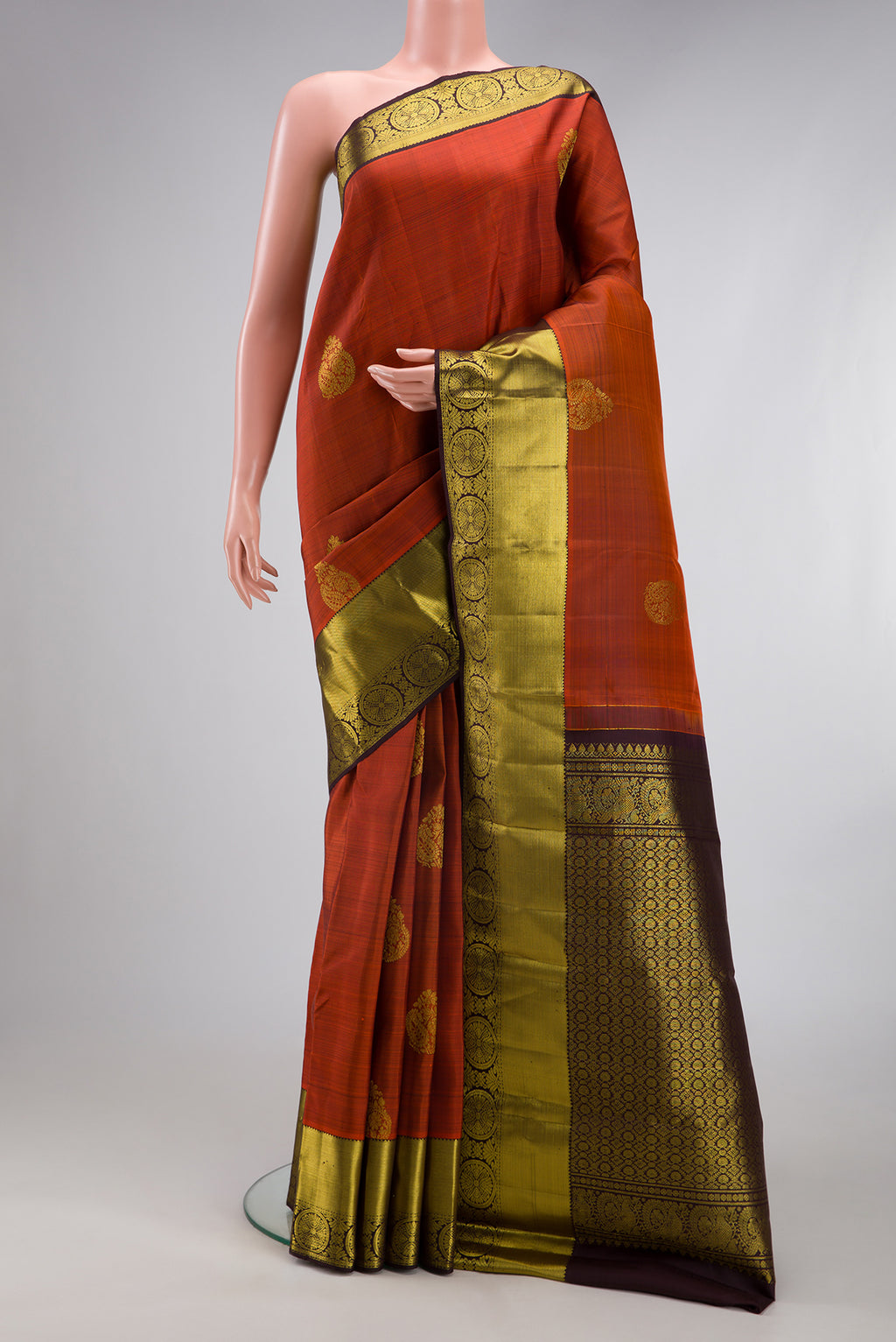 Brick Orange Kanjivaram Silk Saree with Zari Butta on the body and Zari Border.  displayed on a mannequin