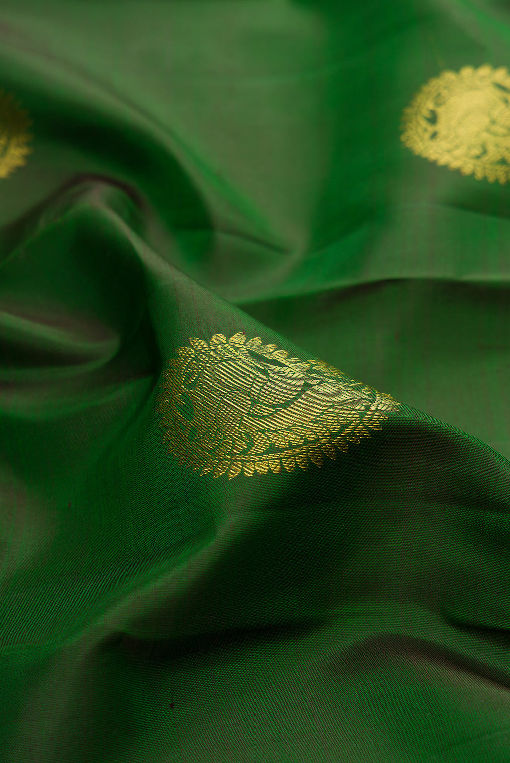 Close up of Bottle Green Kanjivaram Silk Saree with Zari Butta on the body and Zari Border.  displaying folds