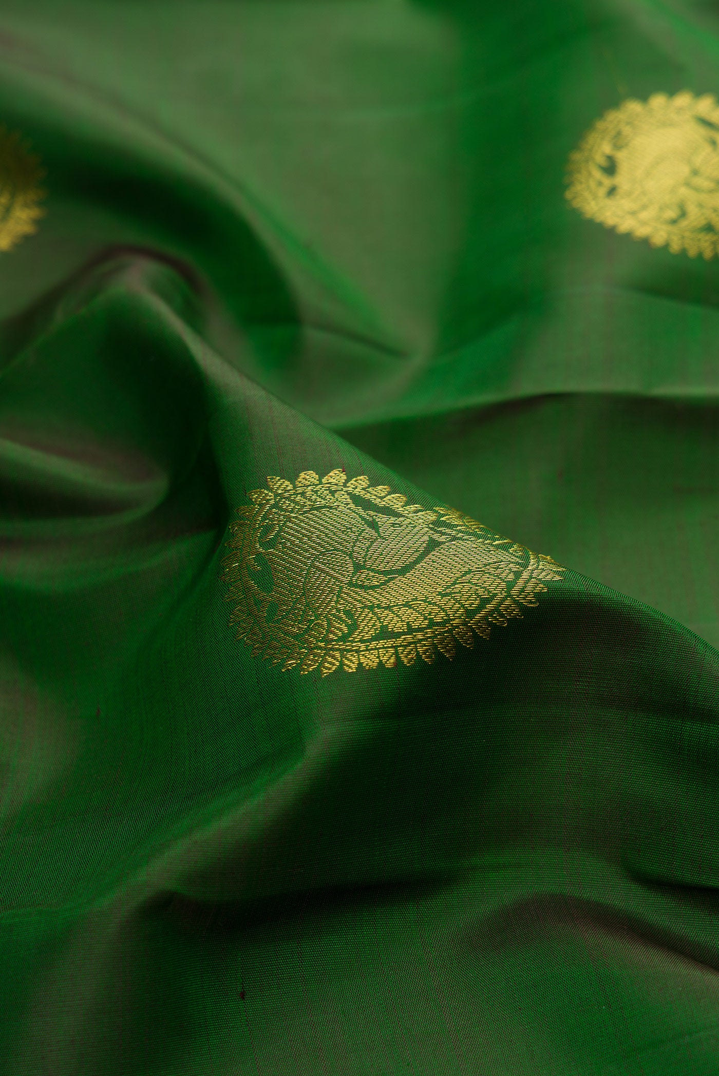 Close up of Bottle Green Kanjivaram Silk Saree with Zari Butta on the body and Zari Border.  displaying folds