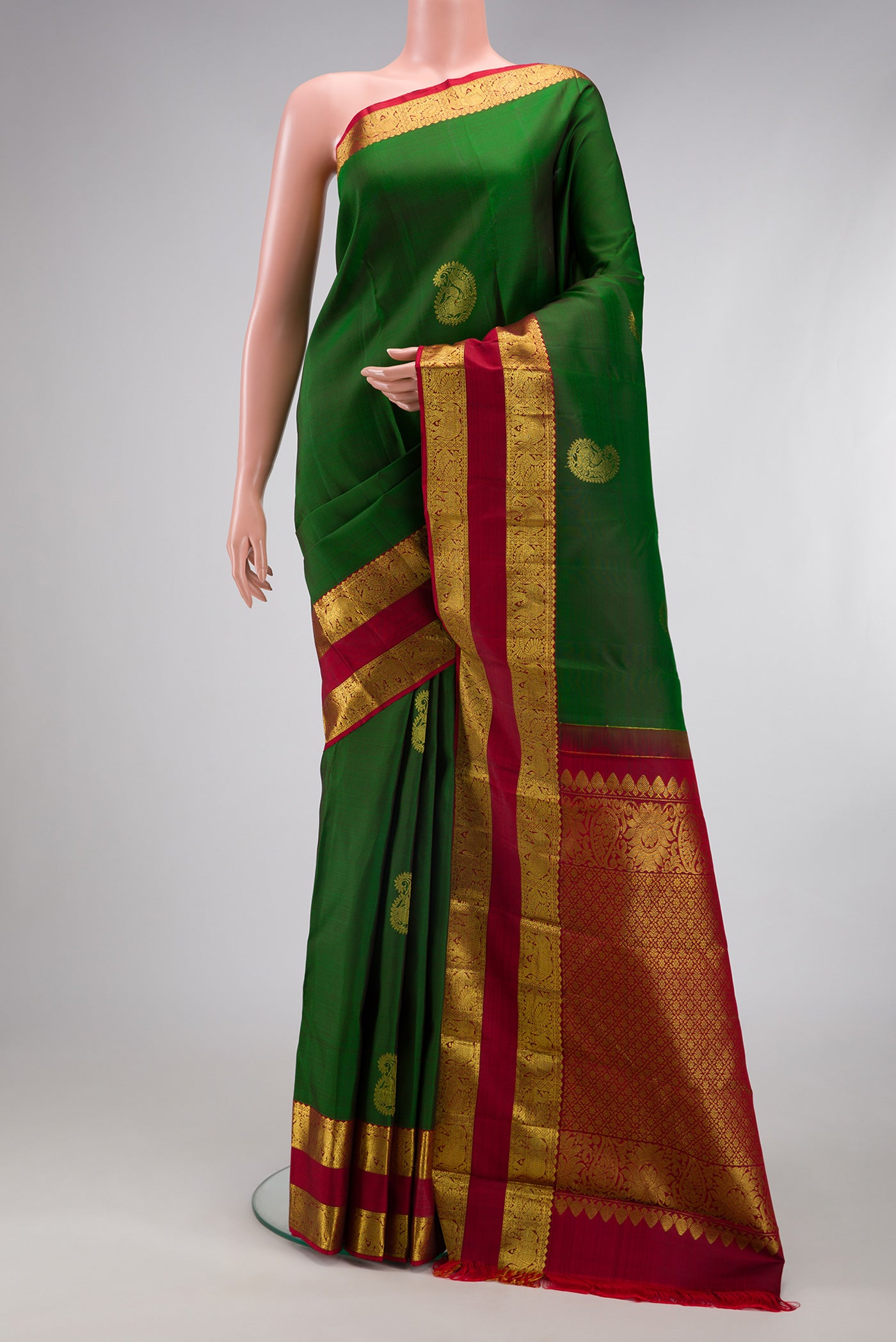 Bottle Green Kanjivaram Silk Saree with Zari Butta on the body and Zari Border.  displayed on a mannequin