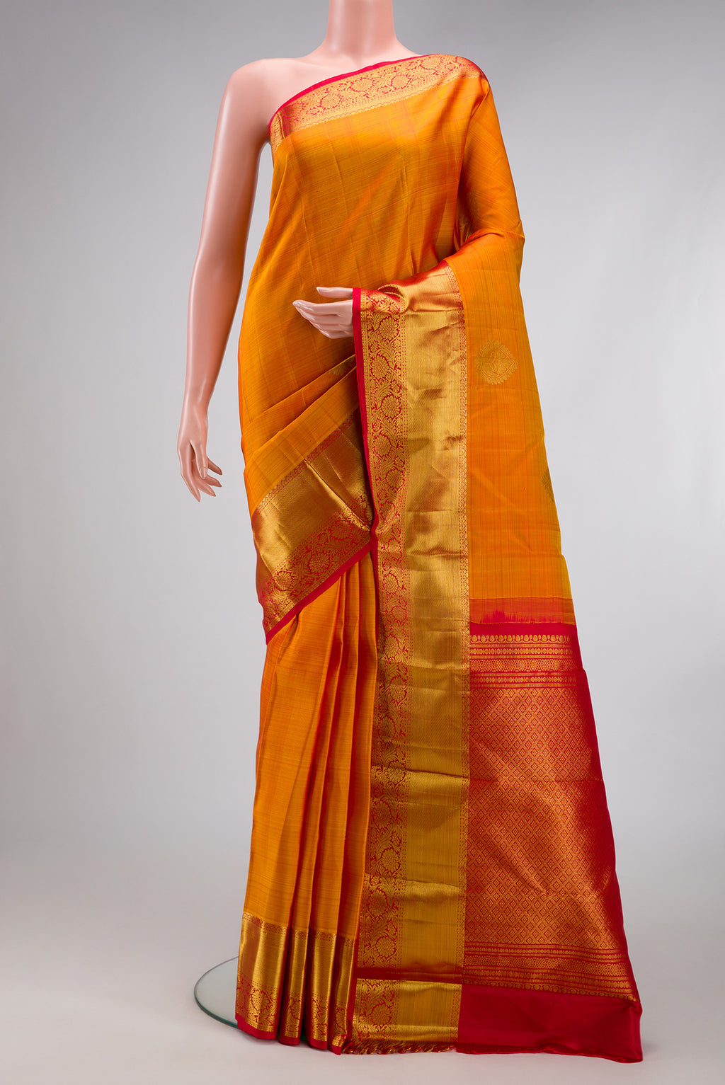 Mustard Kanjivaram Silk Saree with Zari Butta on the body and Zari Border.  displayed on a mannequin