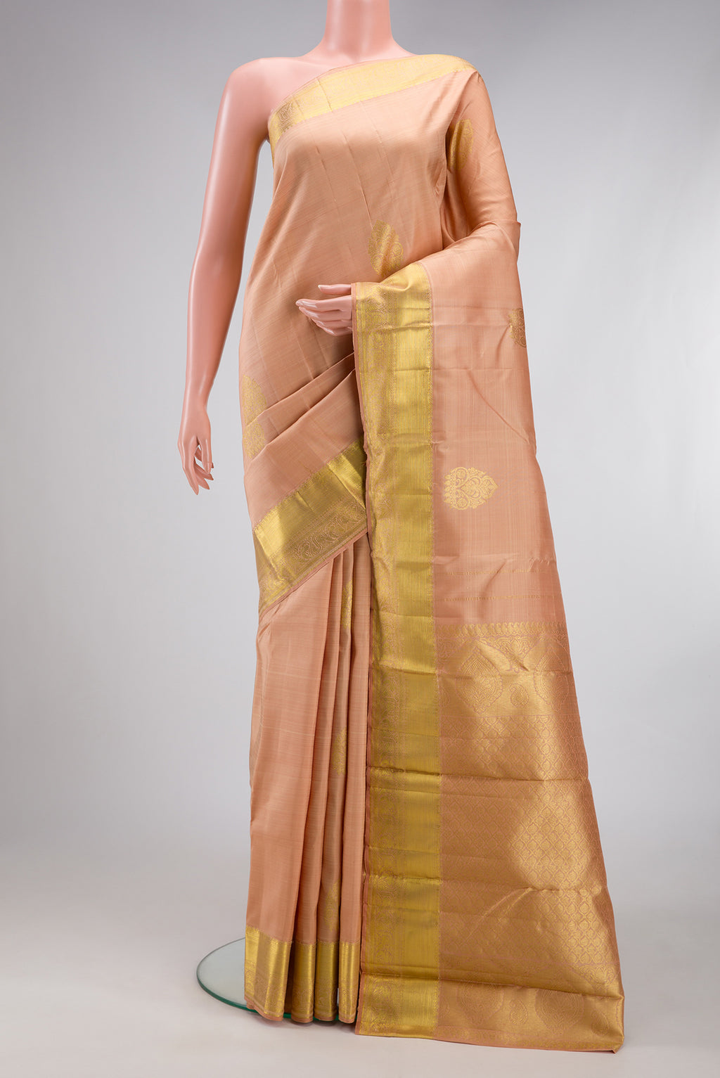 Golden Peach Kanjivaram Silk Saree with Zari Butta on the body and Zari Border.  displayed on a mannequin