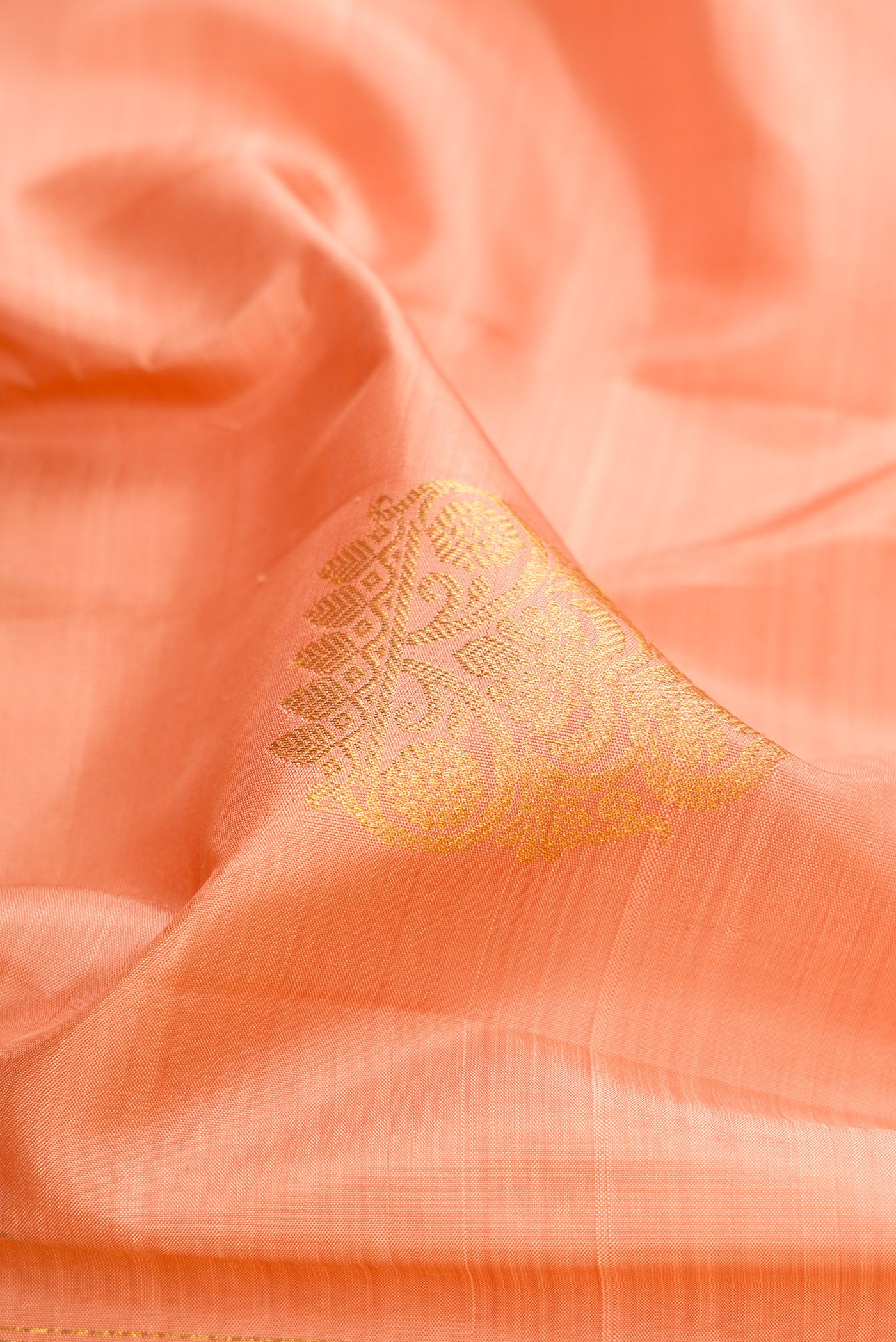 Close up of Peach Kanjivaram Silk Saree with Zari Butta on the body and Zari Border.  displaying folds