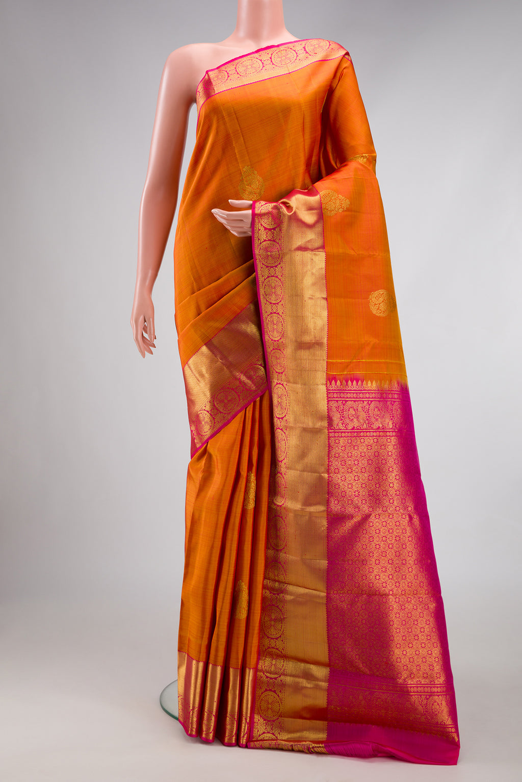 Mustard Kanjivaram Silk Saree with Zari Butta on the body and Zari Border.  displayed on a mannequin
