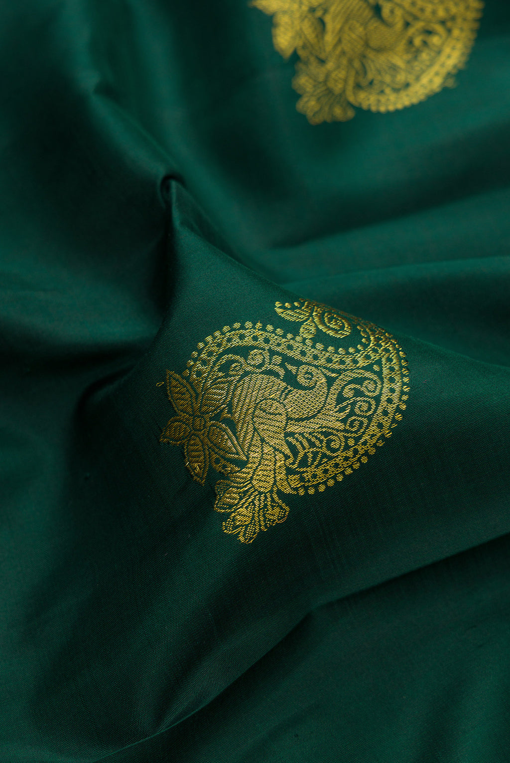 Close up of Bottle Green Kanjivaram Silk Saree with Zari Butta on the body and Zari Border.  displaying folds