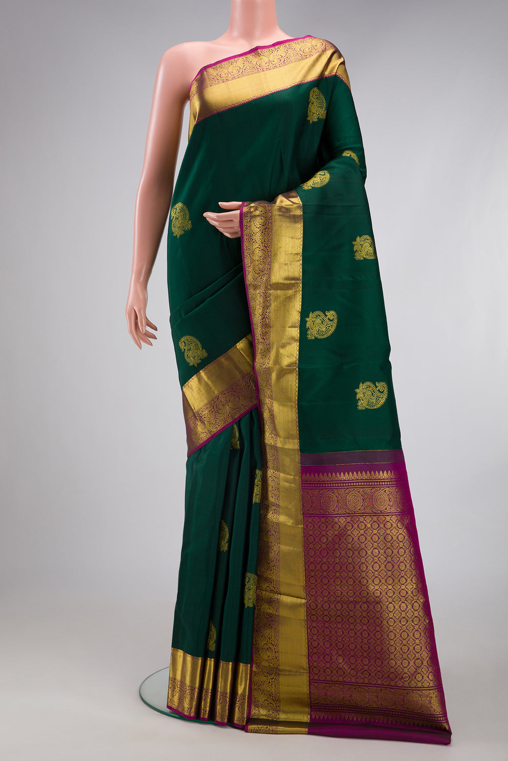 Bottle Green Kanjivaram Silk Saree with Zari Butta on the body and Zari Border.  displayed on a mannequin