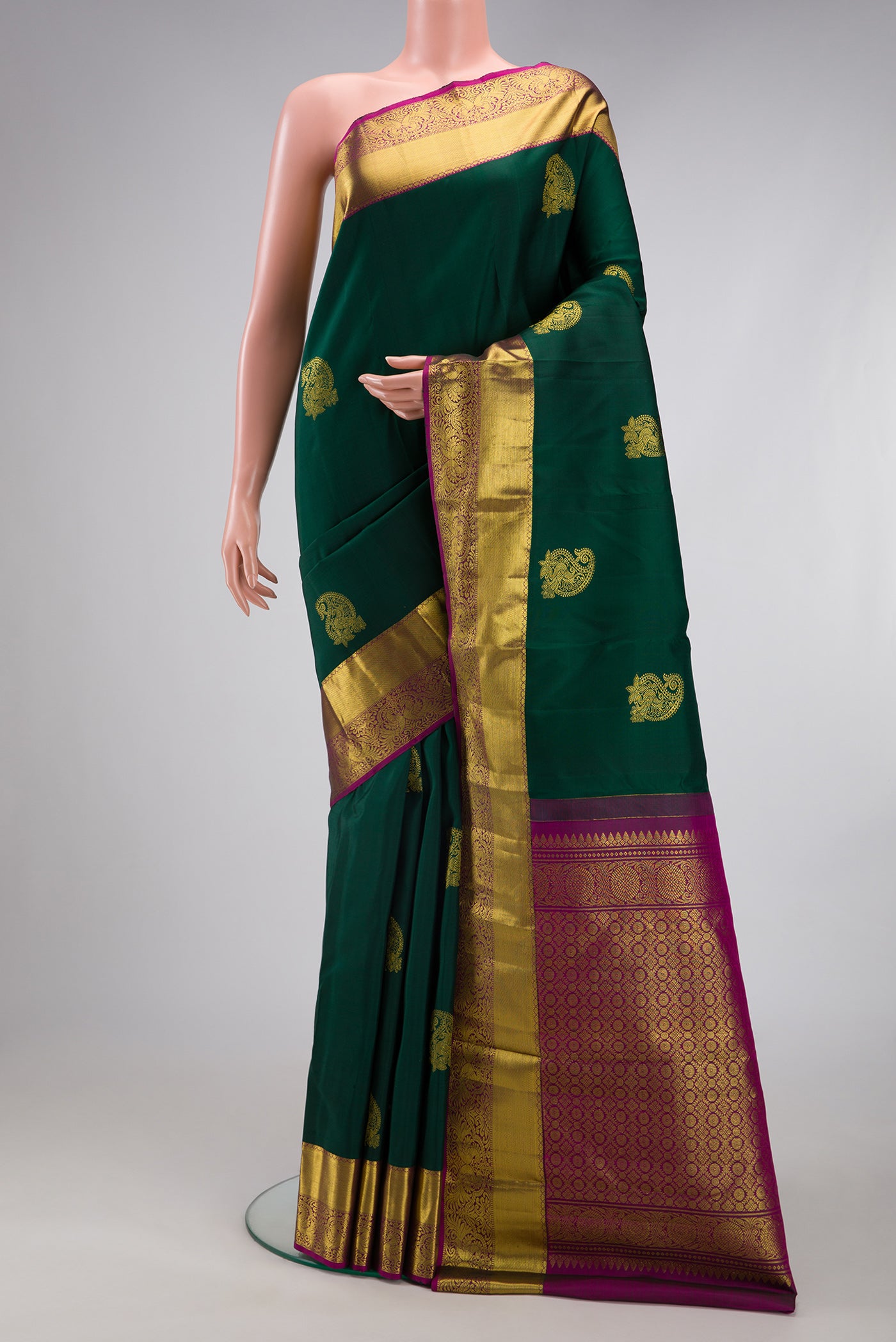 Bottle Green Kanjivaram Silk Saree with Zari Butta on the body and Zari Border.  displayed on a mannequin