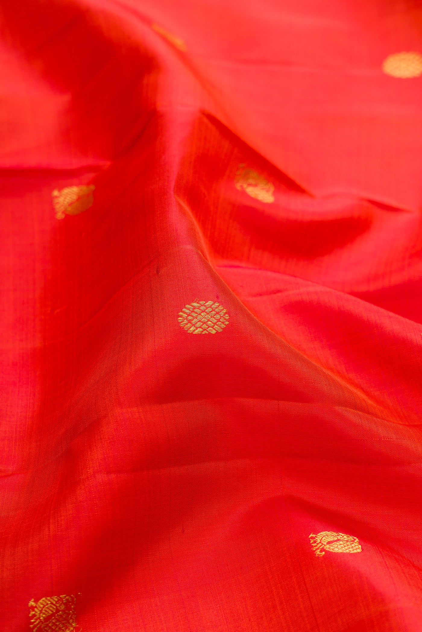 Close up of Orange Kanjivaram Silk Saree with Zari Butta on the body and Zari Border.  displaying folds