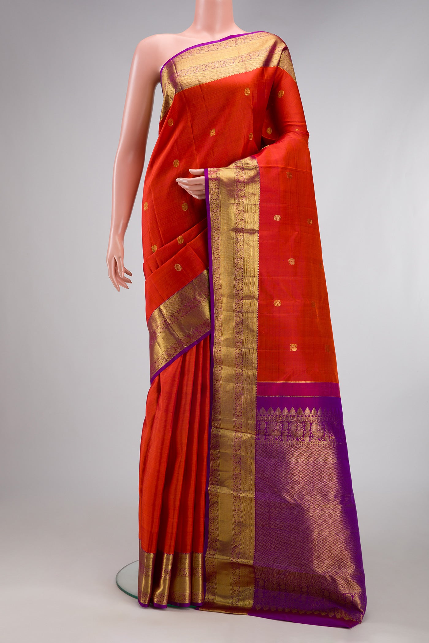 Orange Kanjivaram Silk Saree with Zari Butta on the body and Zari Border.  displayed on a mannequin