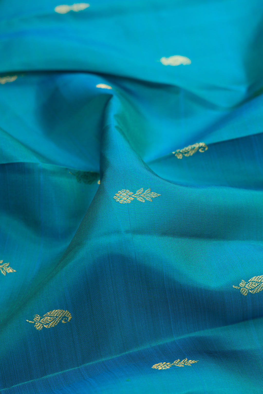 Close up of Peacock Blue Kanjivaram Silk Saree with Zari Butta on the body and Zari Border.  displaying folds