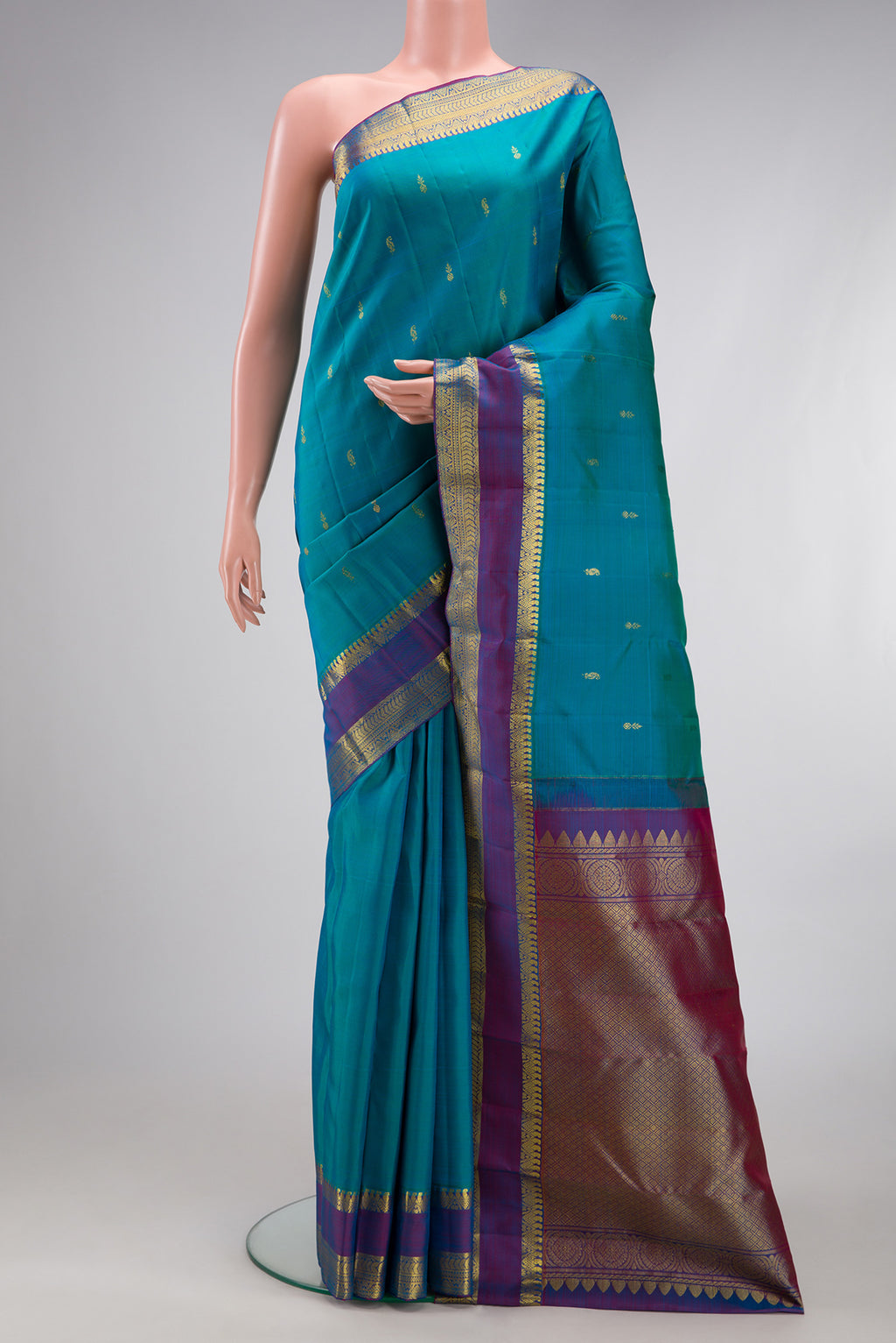 Peacock Blue Kanjivaram Silk Saree with Zari Butta on the body and Zari Border.  displayed on a mannequin