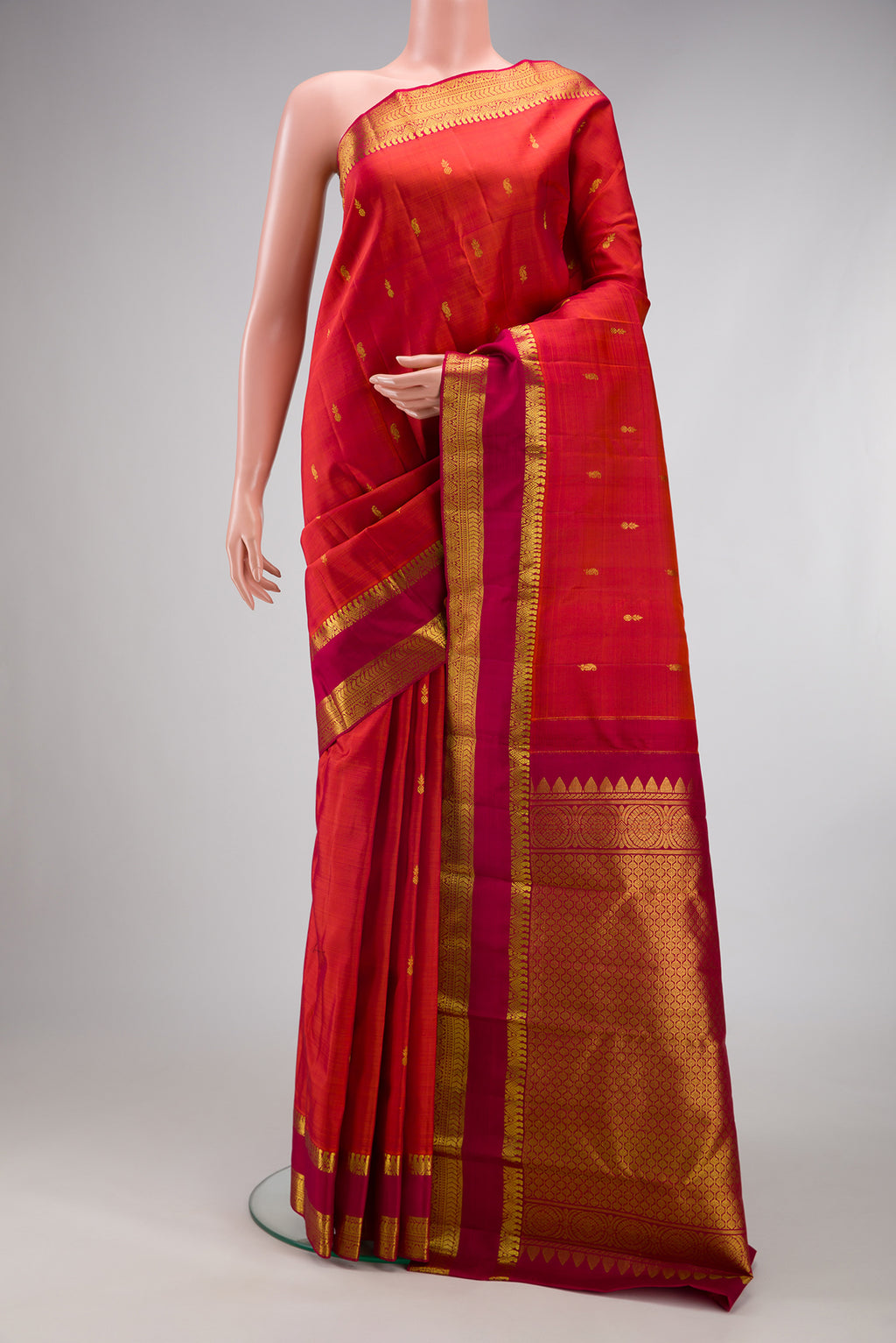 Brick Orange Kanjivaram Silk Saree with Zari Butta on the body and Zari Border.  displayed on a mannequin
