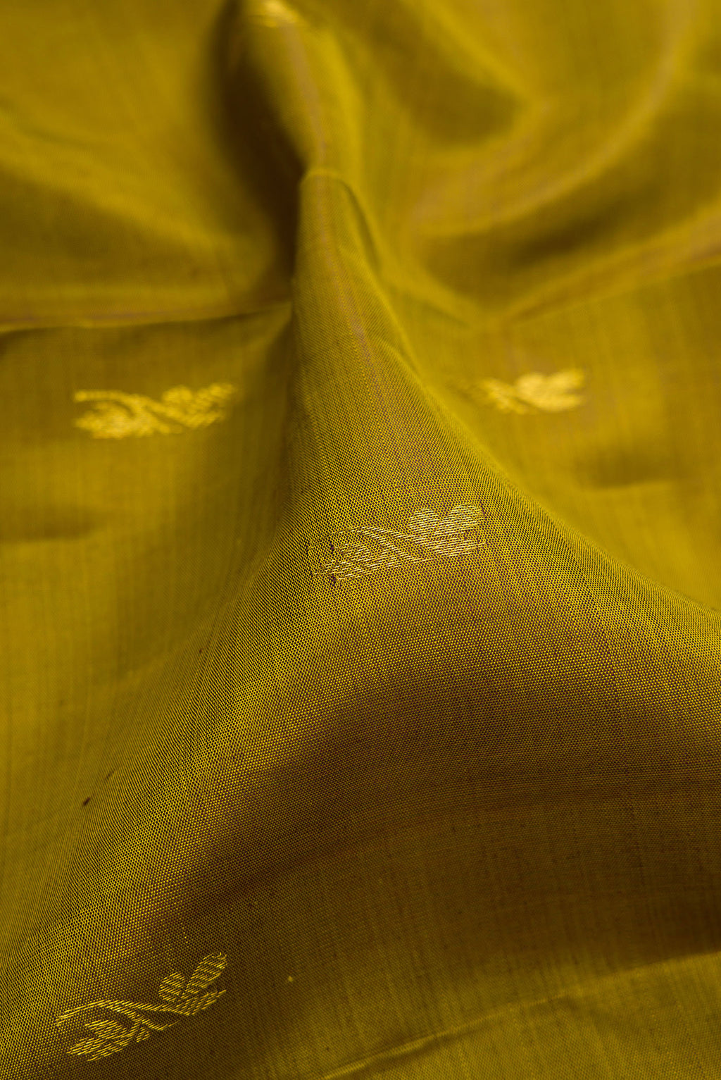 Close up of Mehandi Green Kanjivaram Silk Saree with Zari Butta on the body and Zari Border.  displaying folds