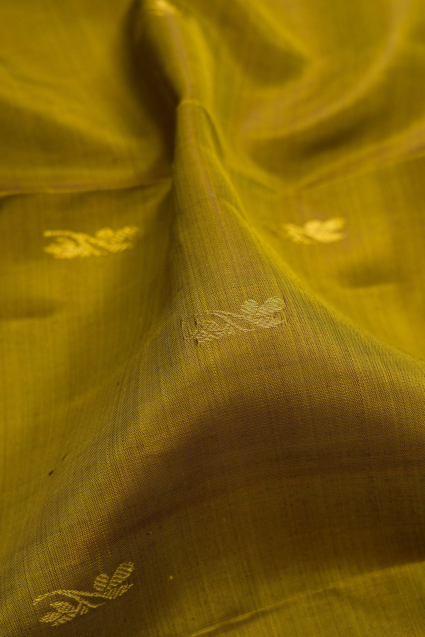 Close up of Mehandi Green Kanjivaram Silk Saree with Zari Butta on the body and Zari Border.  displaying folds