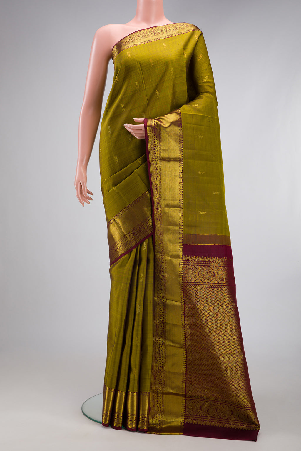 Mehandi Green Kanjivaram Silk Saree with Zari Butta on the body and Zari Border.  displayed on a mannequin
