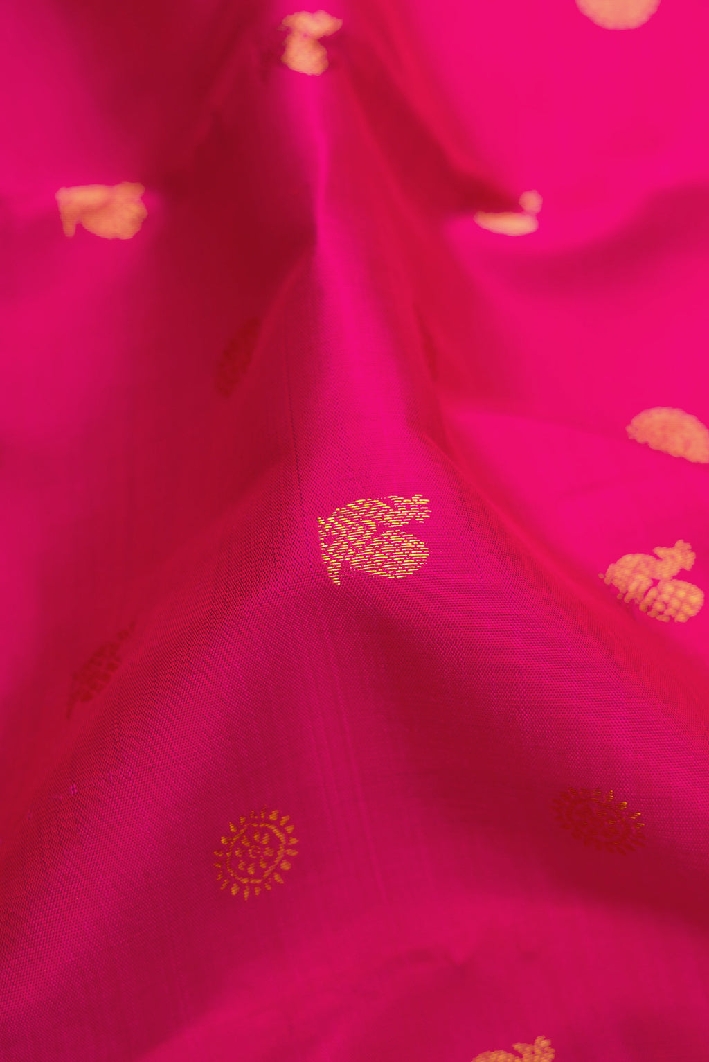 Close up of Rani Pink Kanjivaram Silk Saree with Zari Butta on the body and Zari Border.  displaying folds