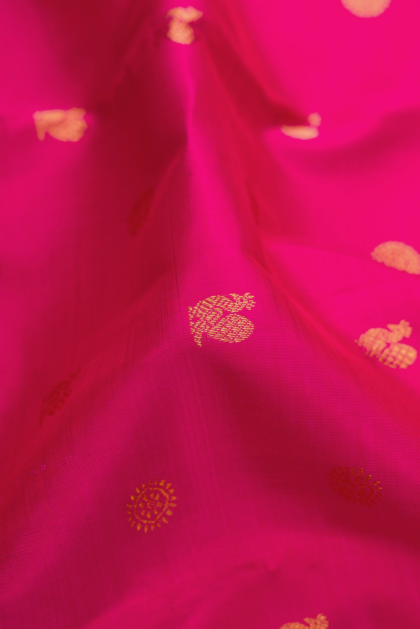 Close up of Rani Pink Kanjivaram Silk Saree with Zari Butta on the body and Zari Border.  displaying folds