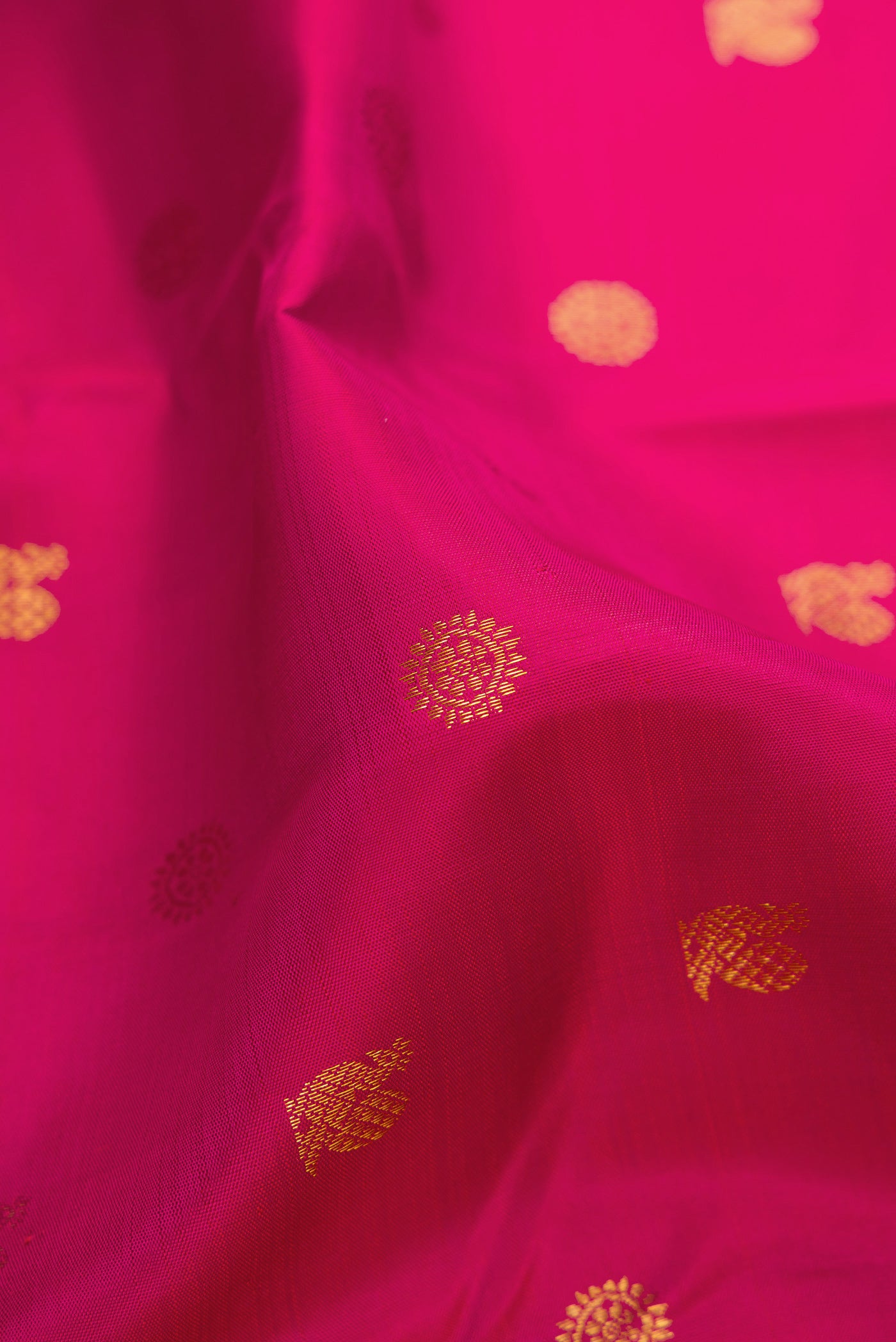 Close up of Dark Pink Kanjivaram Silk Saree with Zari Butta on the body and Zari Border.  displaying folds