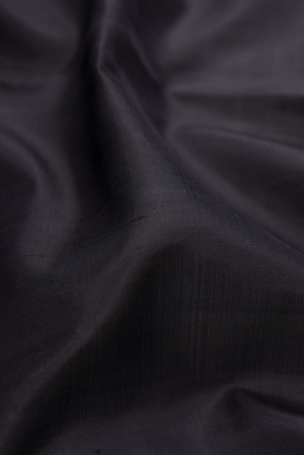 Close up of Black Kanjivaram Silk Saree with Plain Body and Zari Border.  displaying folds