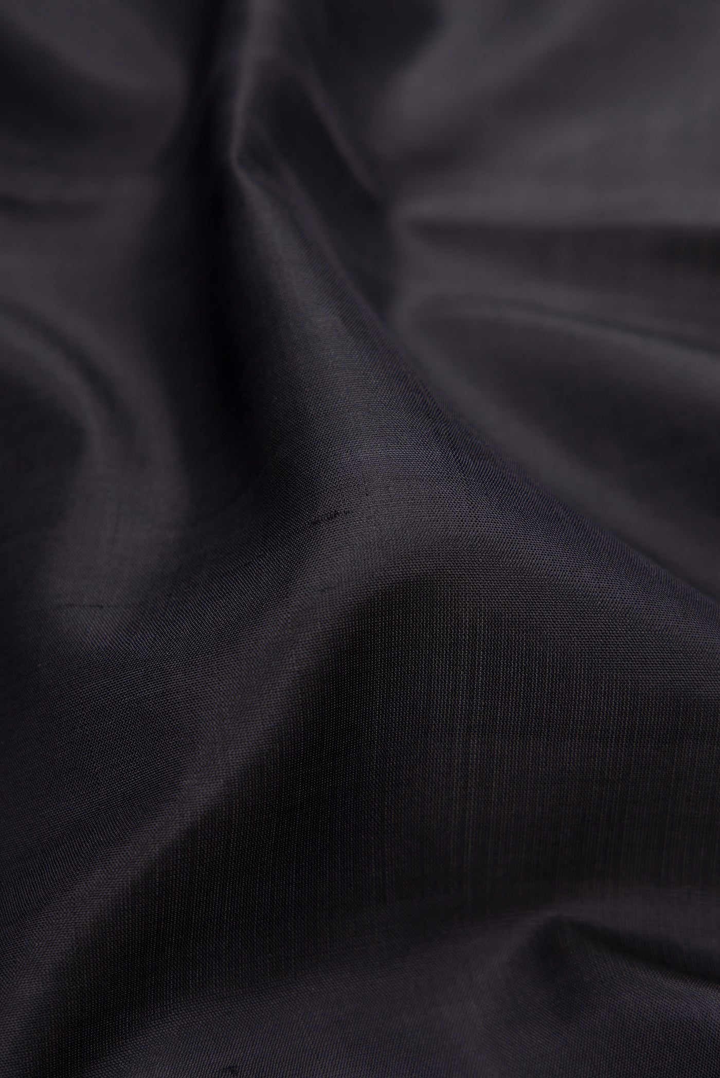 Close up of Black Kanjivaram Silk Saree with Plain Body and Zari Border.  displaying folds