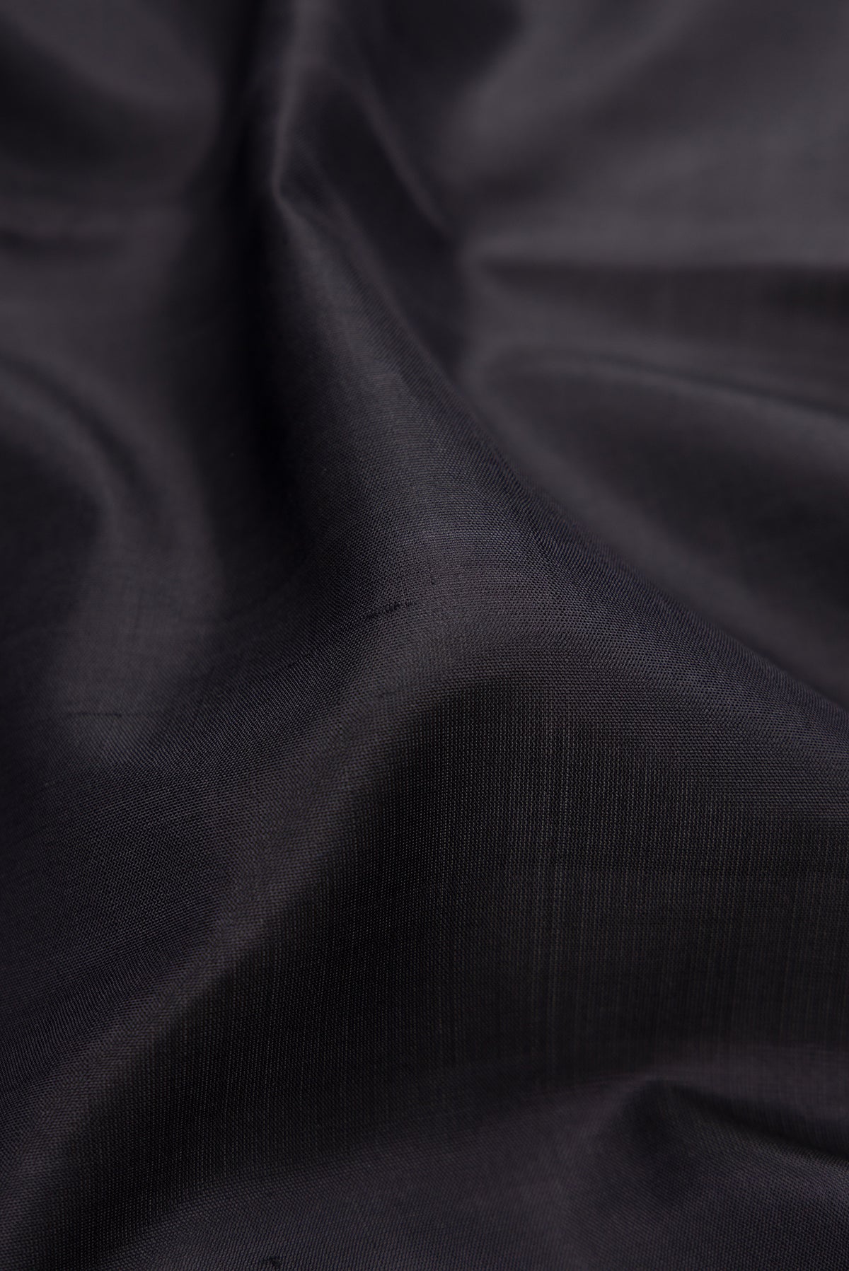 Close up of Black Kanjivaram Silk Saree with Plain Body and Zari Border.  displaying folds