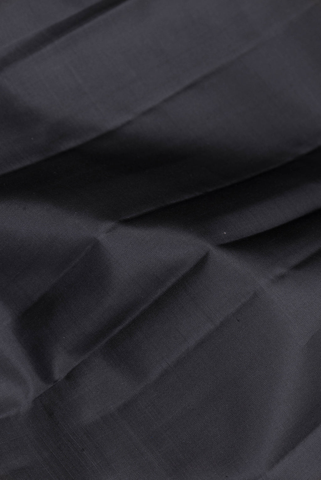 Close up of Black Kanjivaram Silk Saree with Plain Body and Zari Border.  displaying folds