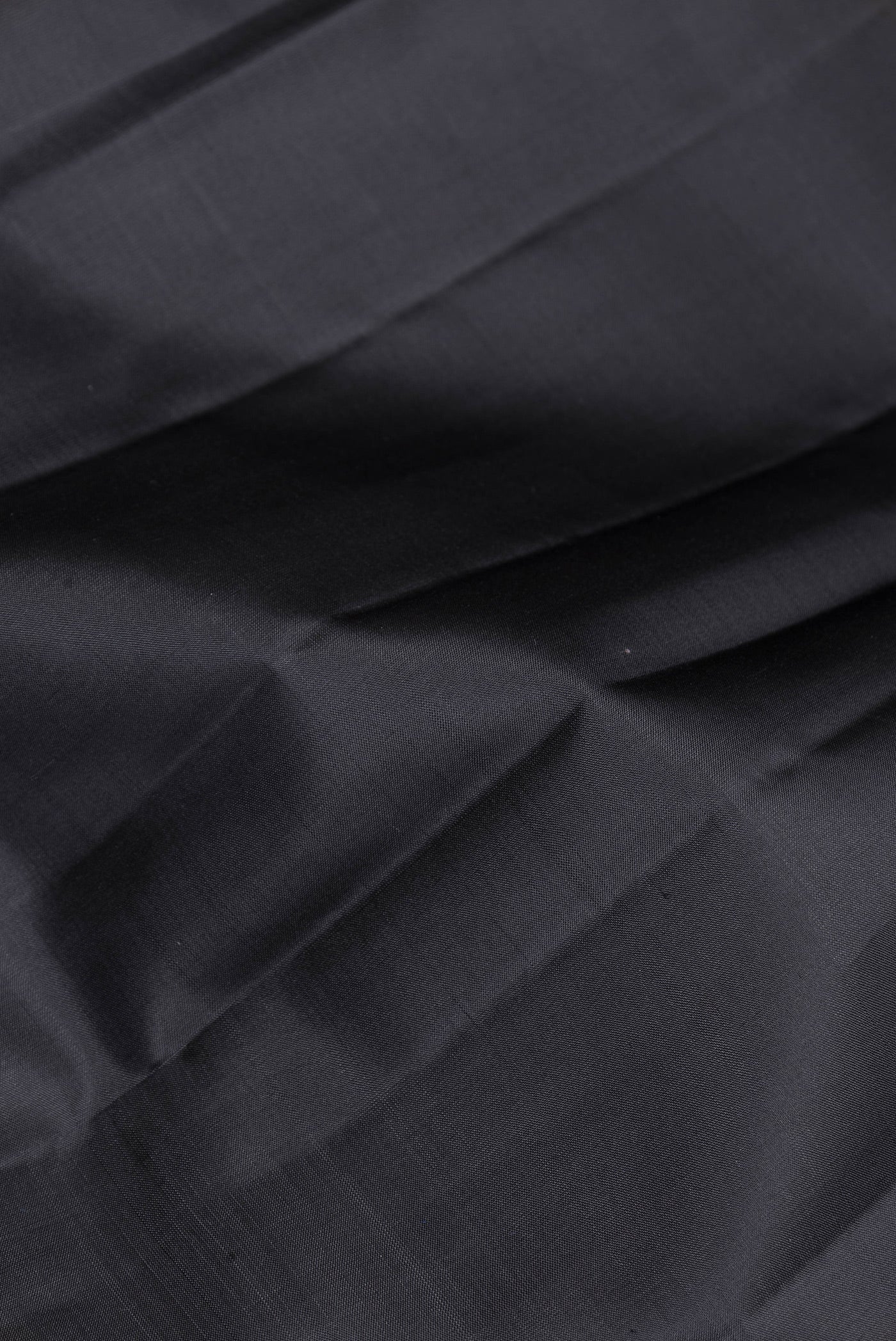 Close up of Black Kanjivaram Silk Saree with Plain Body and Zari Border.  displaying folds