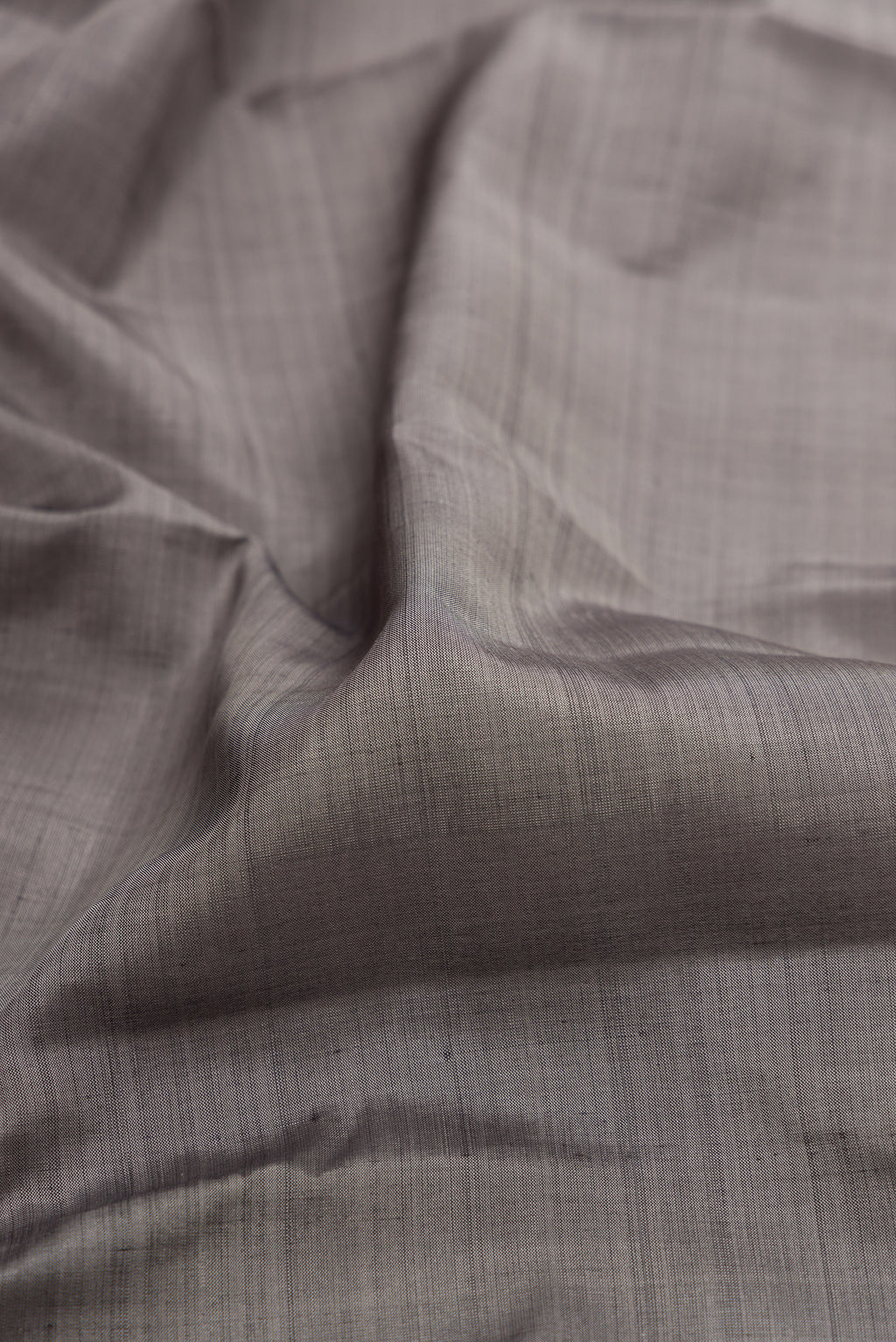 Close up of Grey Kanjivaram Silk Saree with Plain Body and Zari Border.  displaying folds